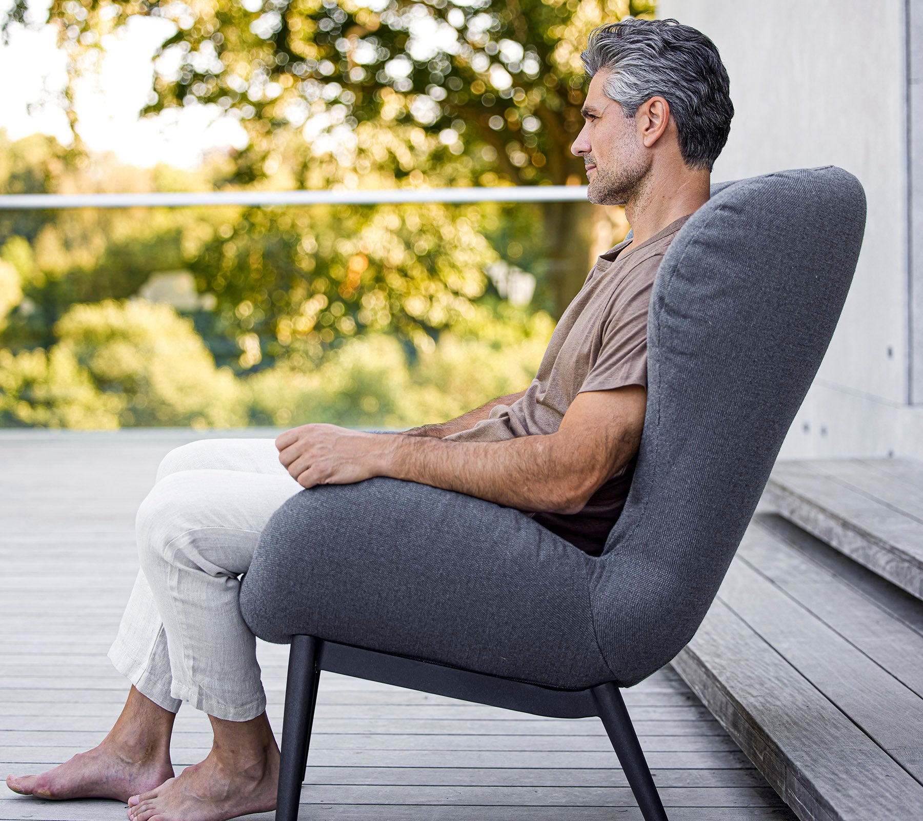 Homme assis confortablement dans une chaise moderne au design épuré, affichant un rembourrage doux et une forme élégante et minimaliste.