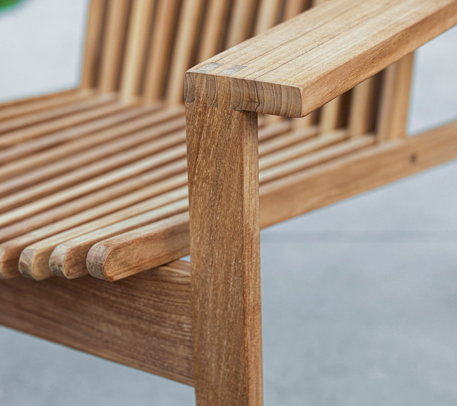 Gros plan d'un banc en bois avec un design à lattes et un accoudoir solide, mettant en valeur le grain naturel du bois et l'artisanat.