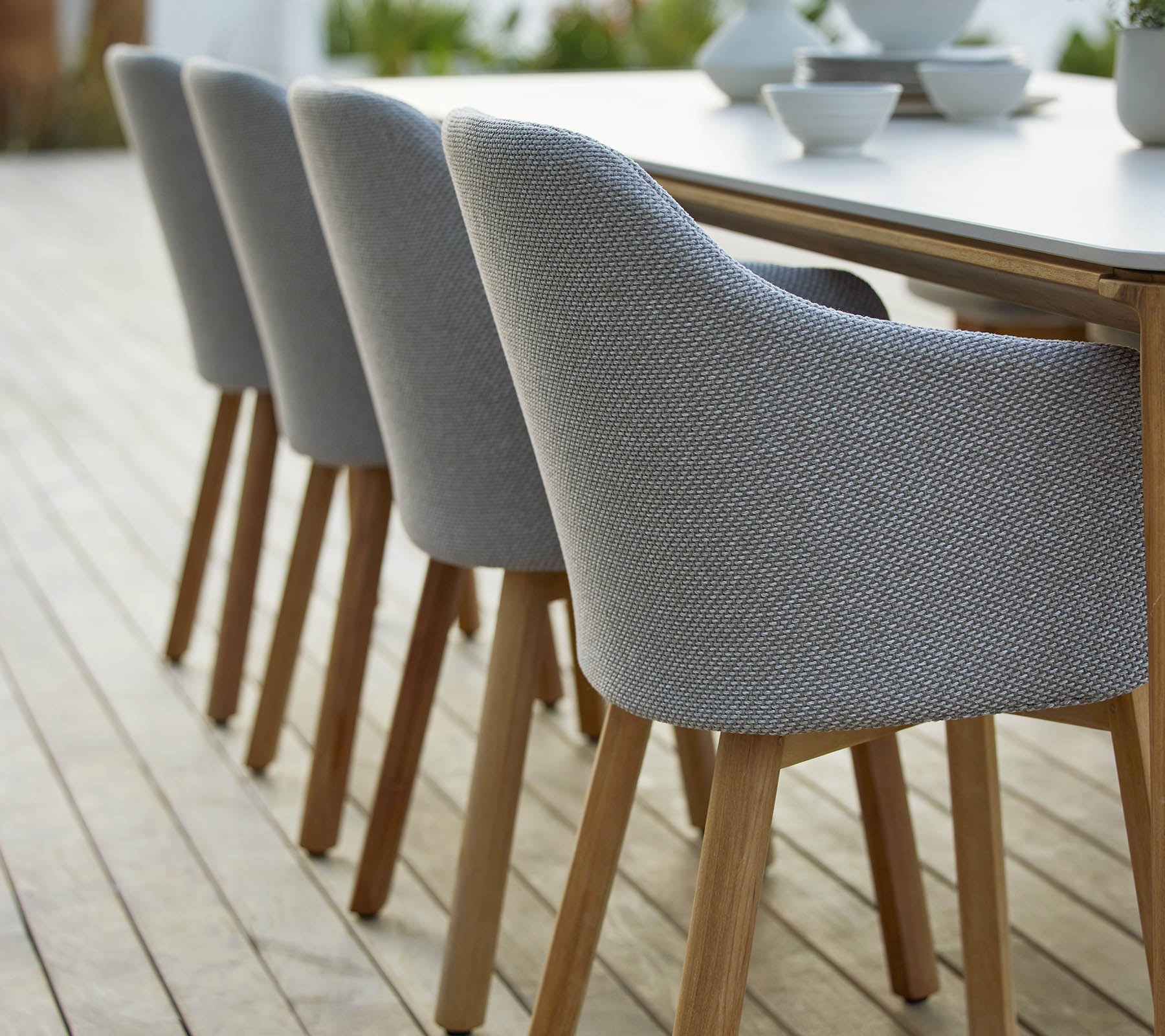Une rangée de chaises modernes rembourrées avec des pieds en bois, disposées à côté d'une table, mettant en valeur un design élégant et contemporain.
