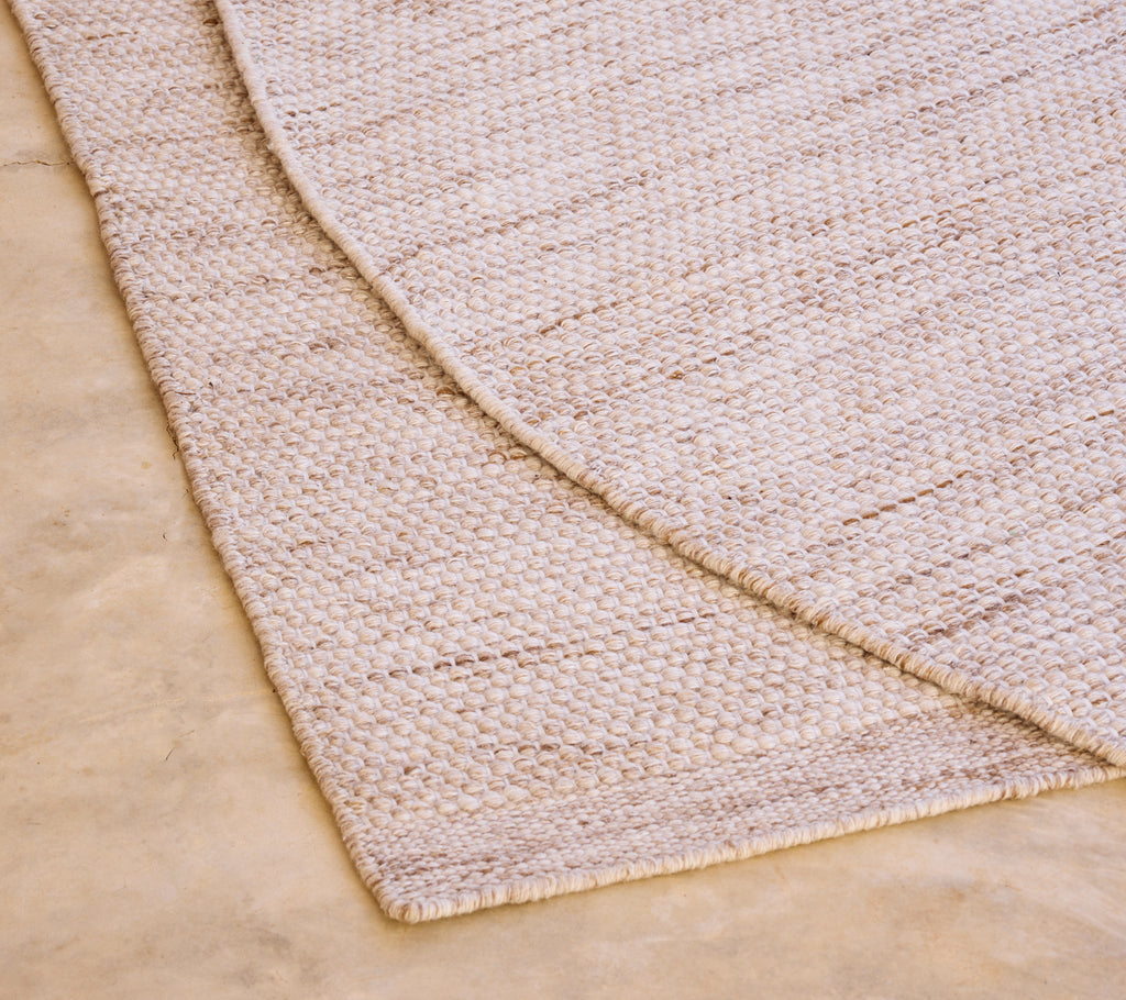Tapis beige avec un motif texturé sur un sol clair.