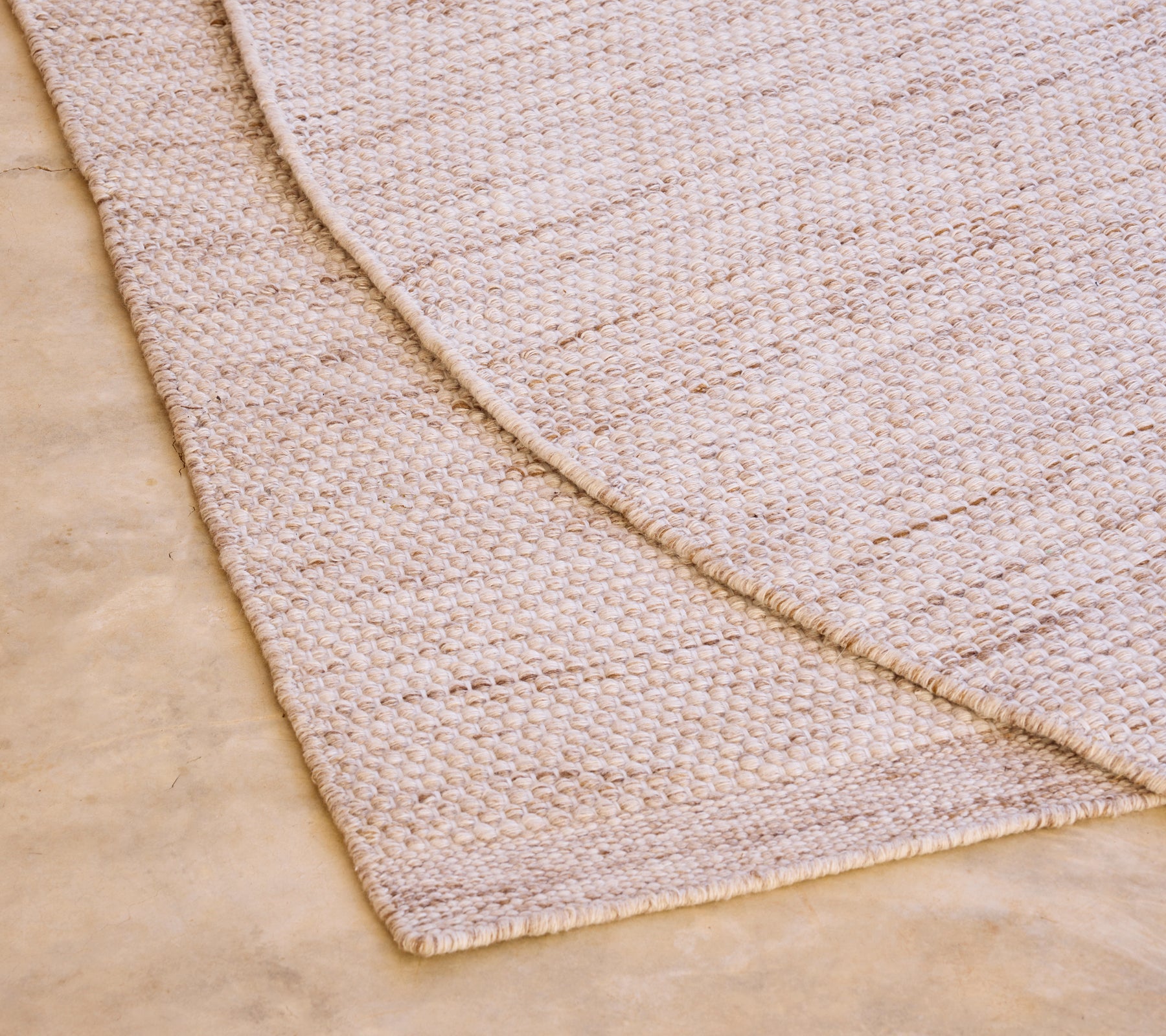 Tapis beige avec un motif texturé sur un sol clair.