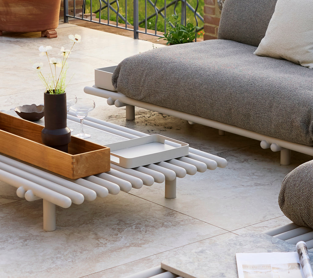 Un petit plateau rectangulaire sur une table basse plateforme avec des objets décoratifs et un design minimaliste.