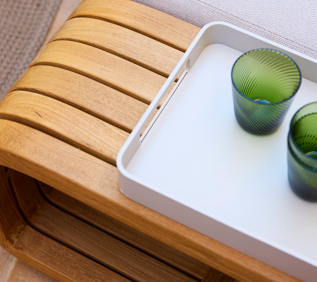 Petit plateau rectangulaire de club en couleur sable, tenant deux verres texturés verts, reposant sur une surface en bois.