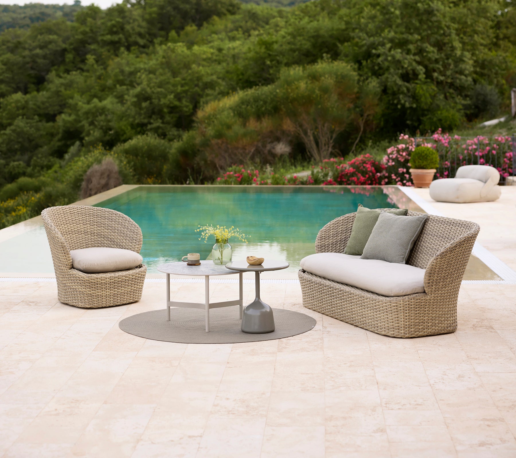 Mobilier de salon côtier avec des coussins doux, associé à une table basse Twist et une table basse Glaze, entouré d'une verdure luxuriante et d'une piscine.