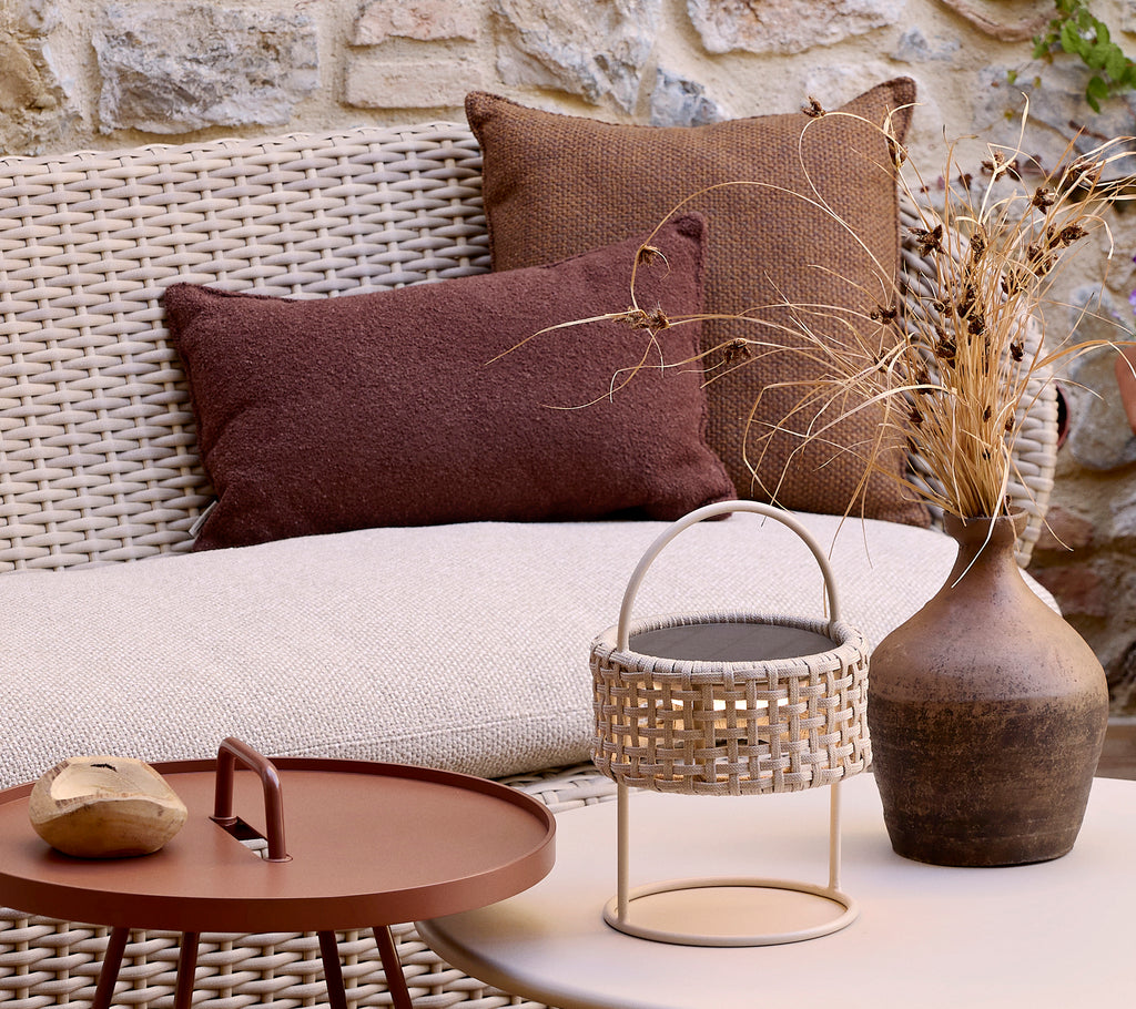 Canapé côtier douillet avec des coussins texturés, un vase décoratif et une table basse élégante avec un panier tissé et une pierre lisse.