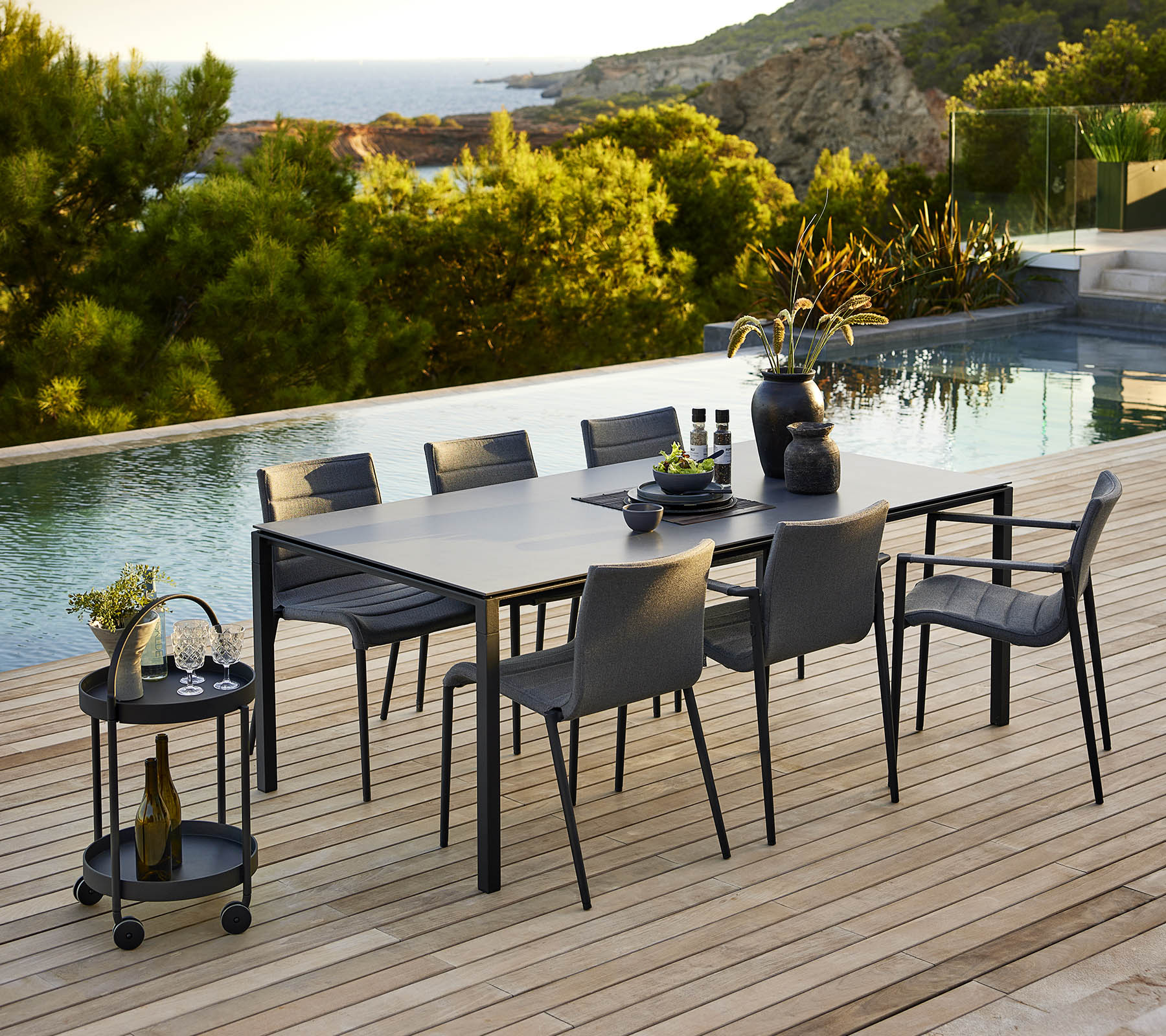 Installation de salle à manger élégante avec une table élégante et des chaises assorties, complétée par des accessoires décoratifs et un arrière-plan extérieur serein.