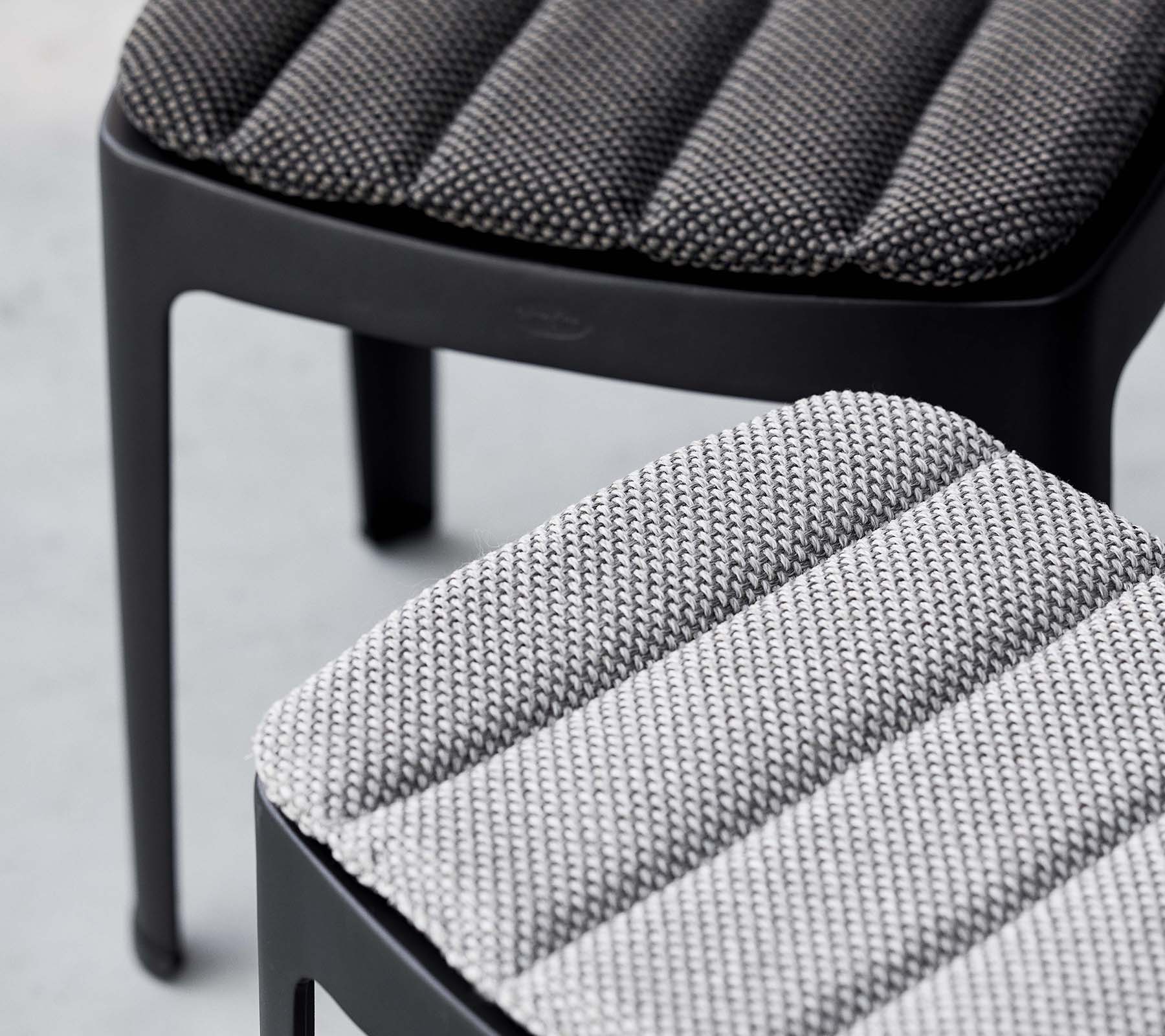 Deux tabourets élégants avec un revêtement texturé dans des nuances de gris contrastées, présentant un design moderne aux lignes épurées.