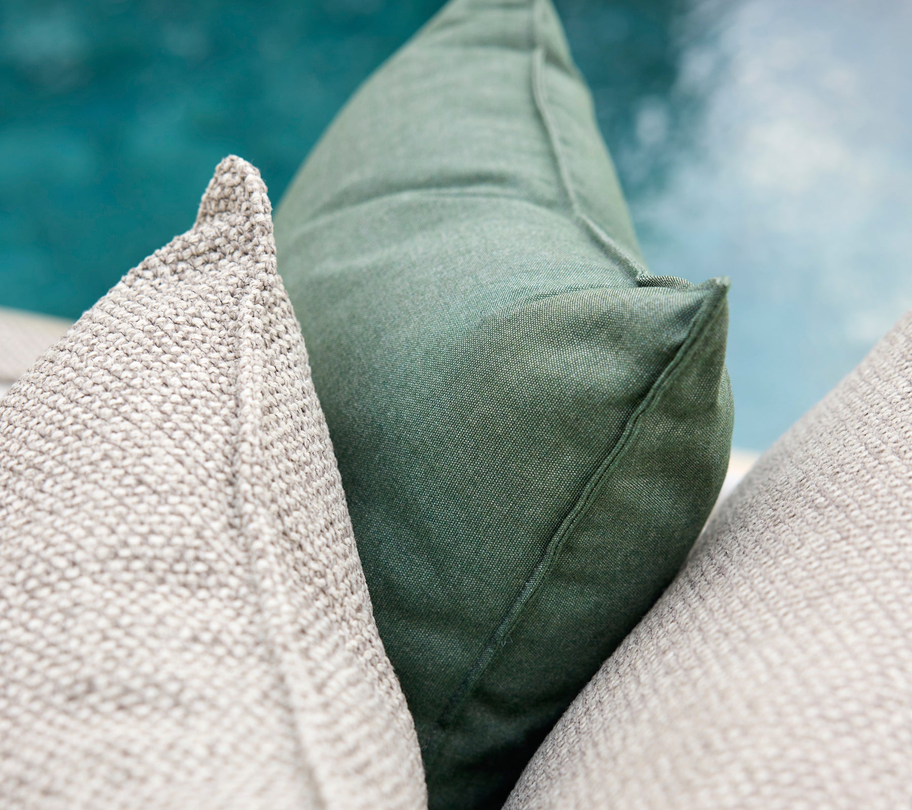 Des coussins verts et gris disposés ensemble.