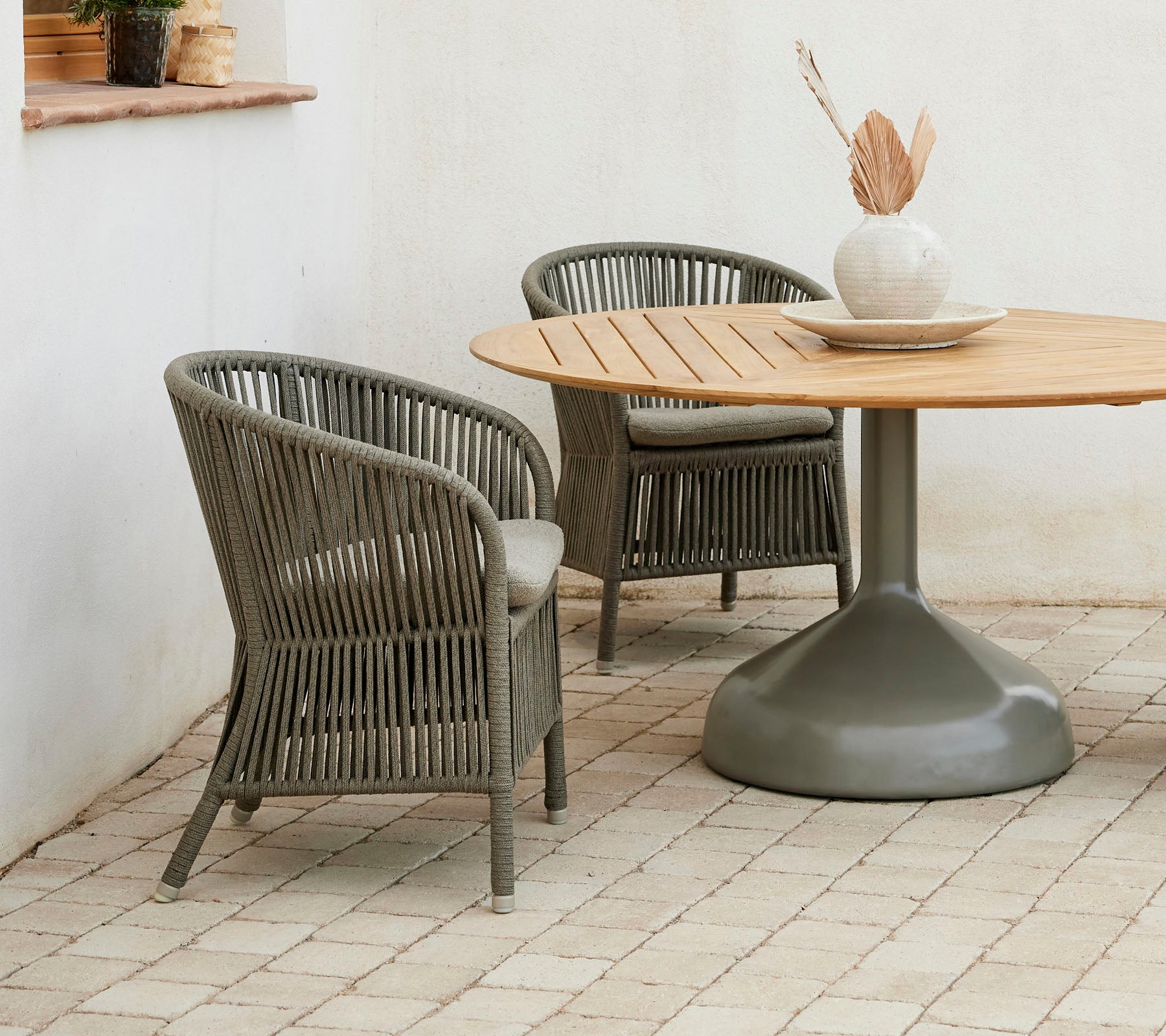 Deux chaises Derby élégantes accompagnées d'une table de salle à manger ronde Glaze, avec une palette de couleurs neutres et un vase décoratif.