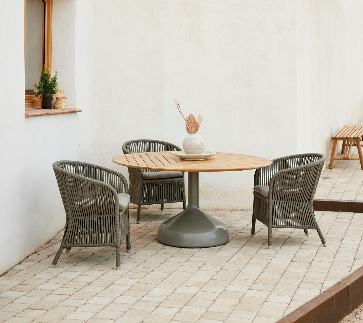 Un agencement de salle à manger élégant avec une table ronde en bois entourée de chaises Derby élégantes, créant une atmosphère accueillante.
