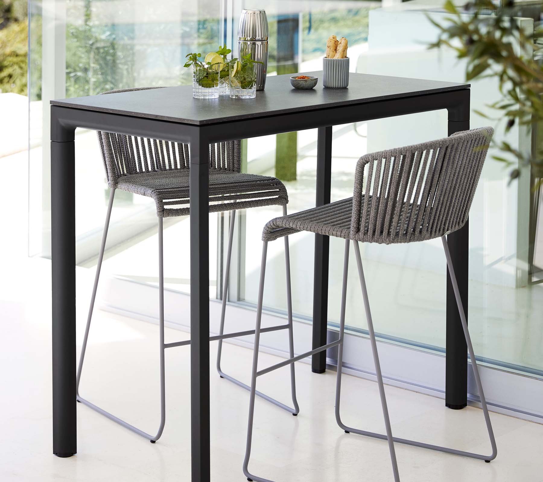 Table moderne avec deux tabourets élégants, présentant un design épuré, assortie de plantes décoratives et d’accessoires de table minimalistes.