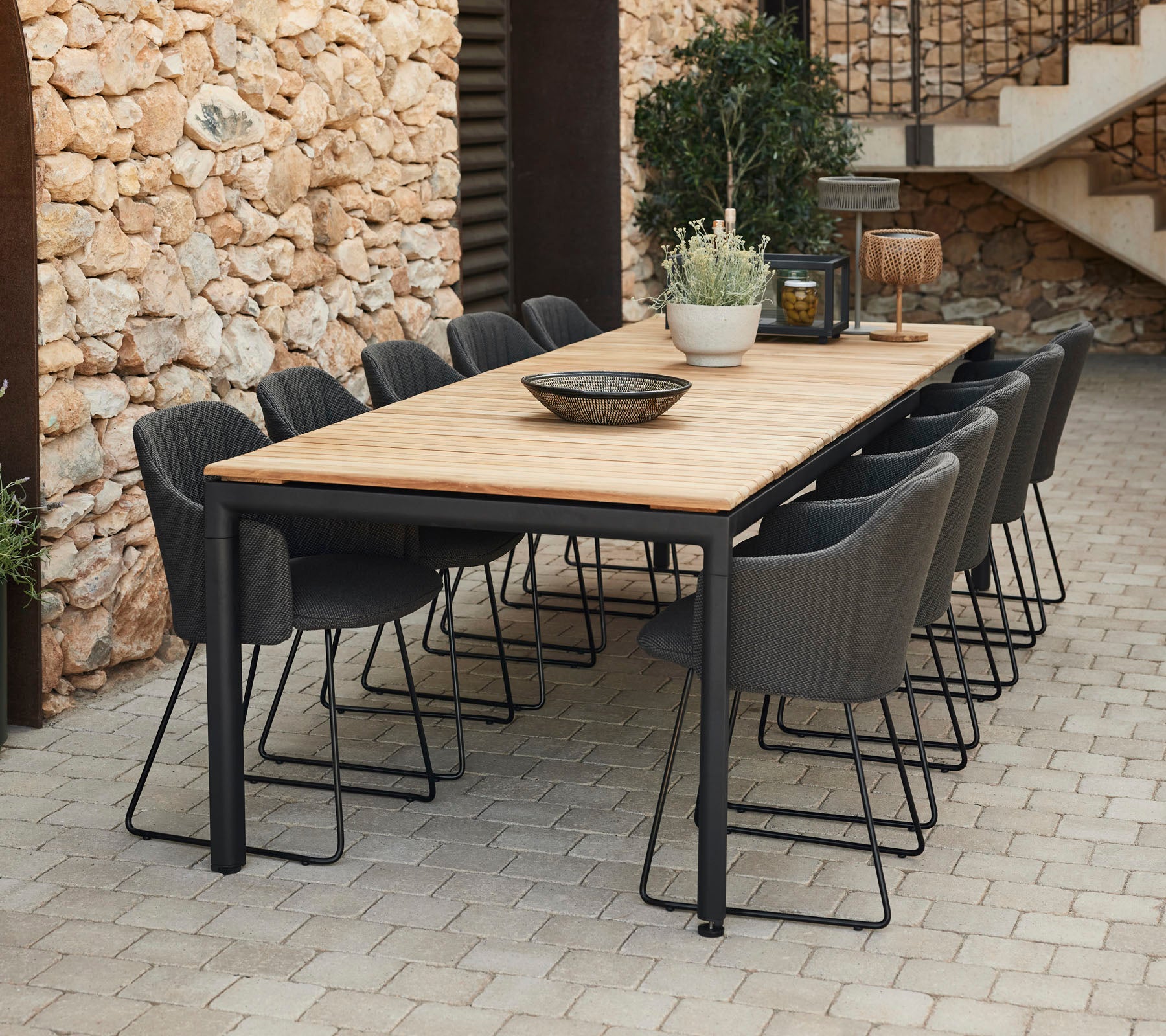 Table à manger élégante avec un plateau en bois et des pieds en métal noir, entourée de chaises grises, parfaite pour les rassemblements.