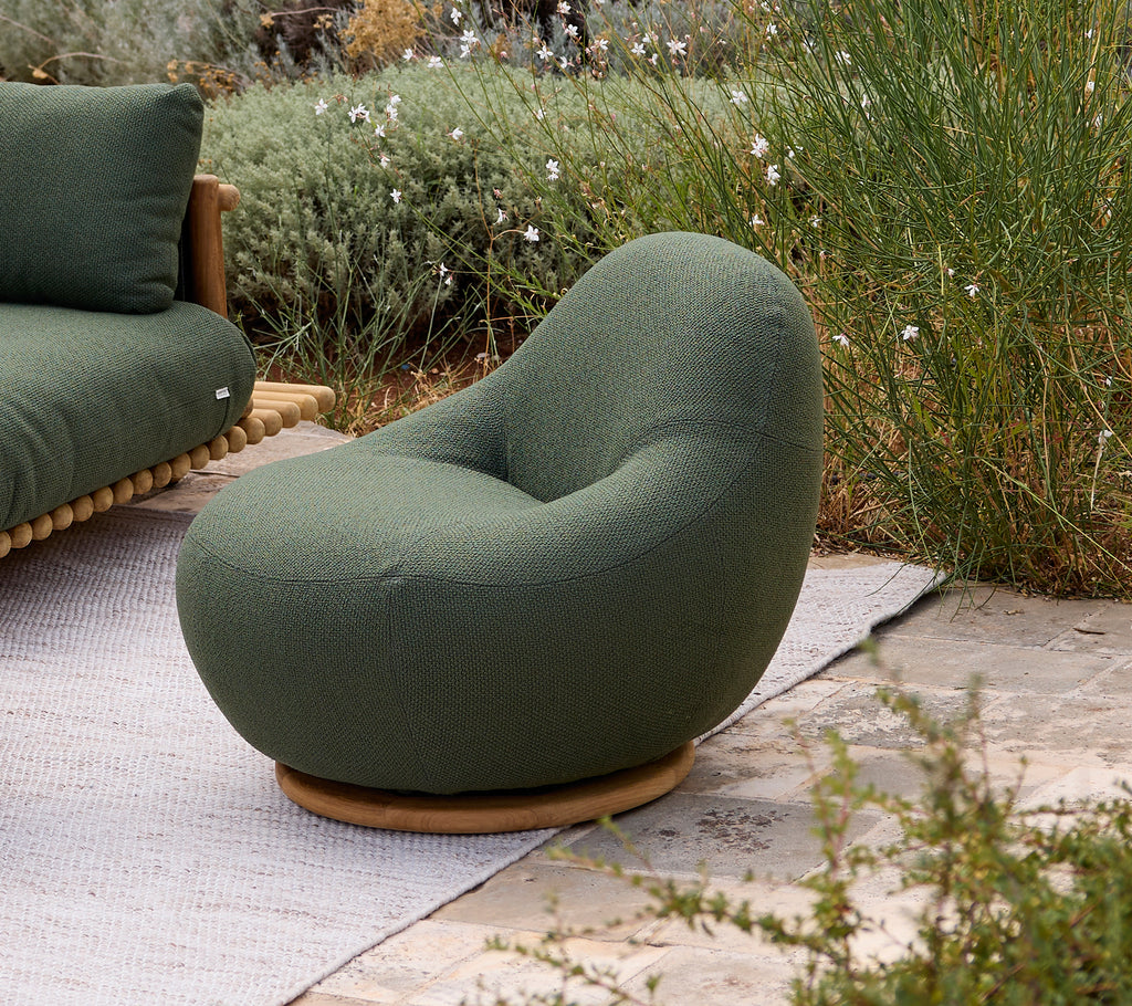 Une chaise vert foncé avec un design arrondi dans un cadre de salon moderne.