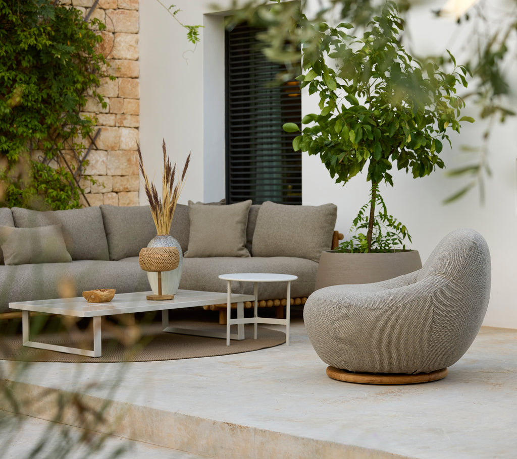 Espace salon moderne avec un canapé d'angle gris, une table basse blanche et une chaise ronde.