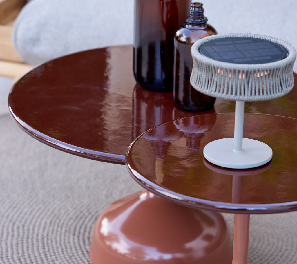 Table brune moderne avec une lampe blanche et des bouteilles sur une surface texturée.