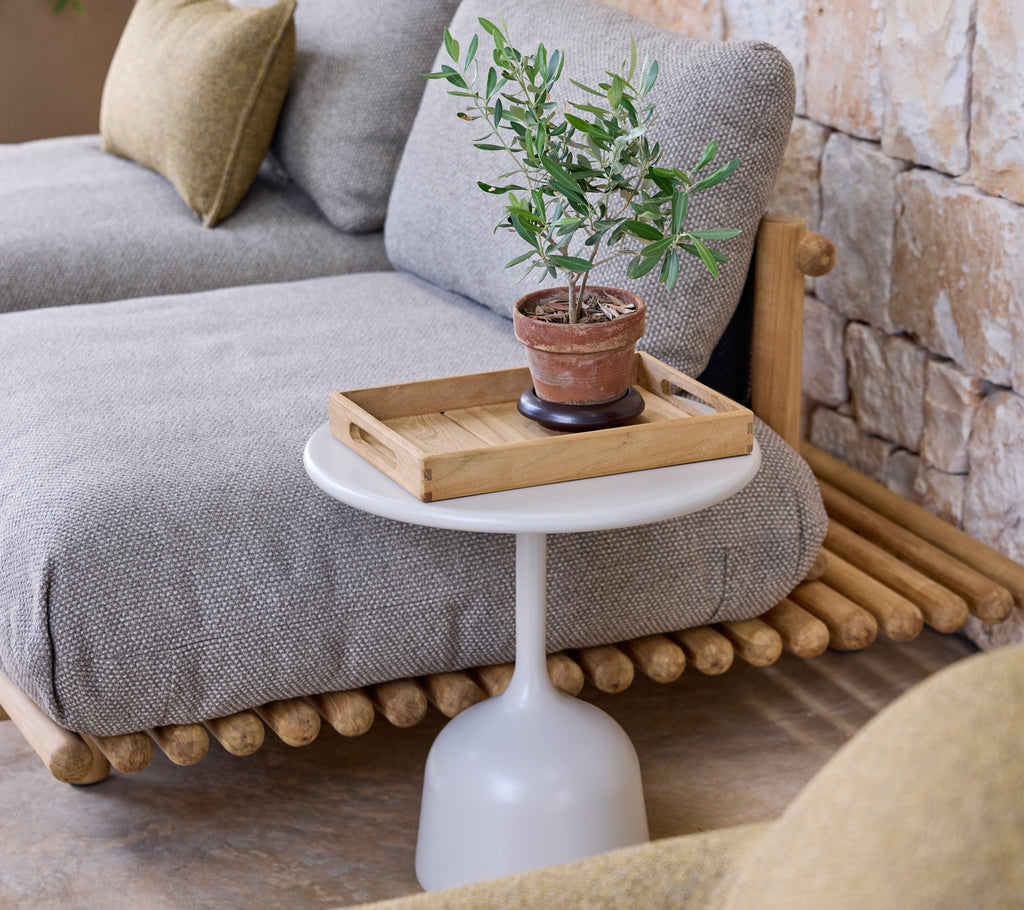 Aménagement moderne du salon avec un canapé gris, une table d'appoint blanche et une plante verte.