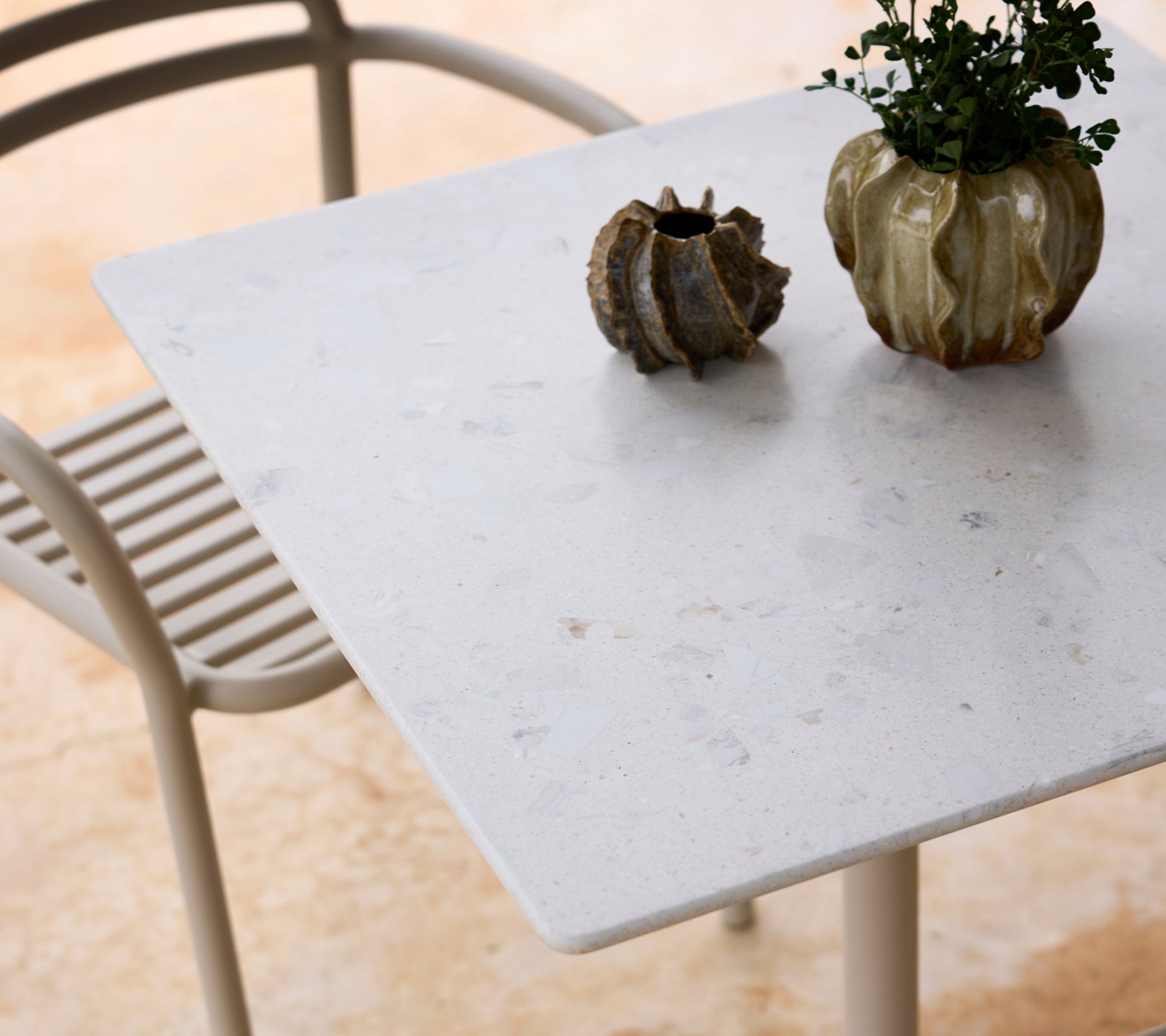 Table blanche avec une chaise grise et un centre de table en plante verte.