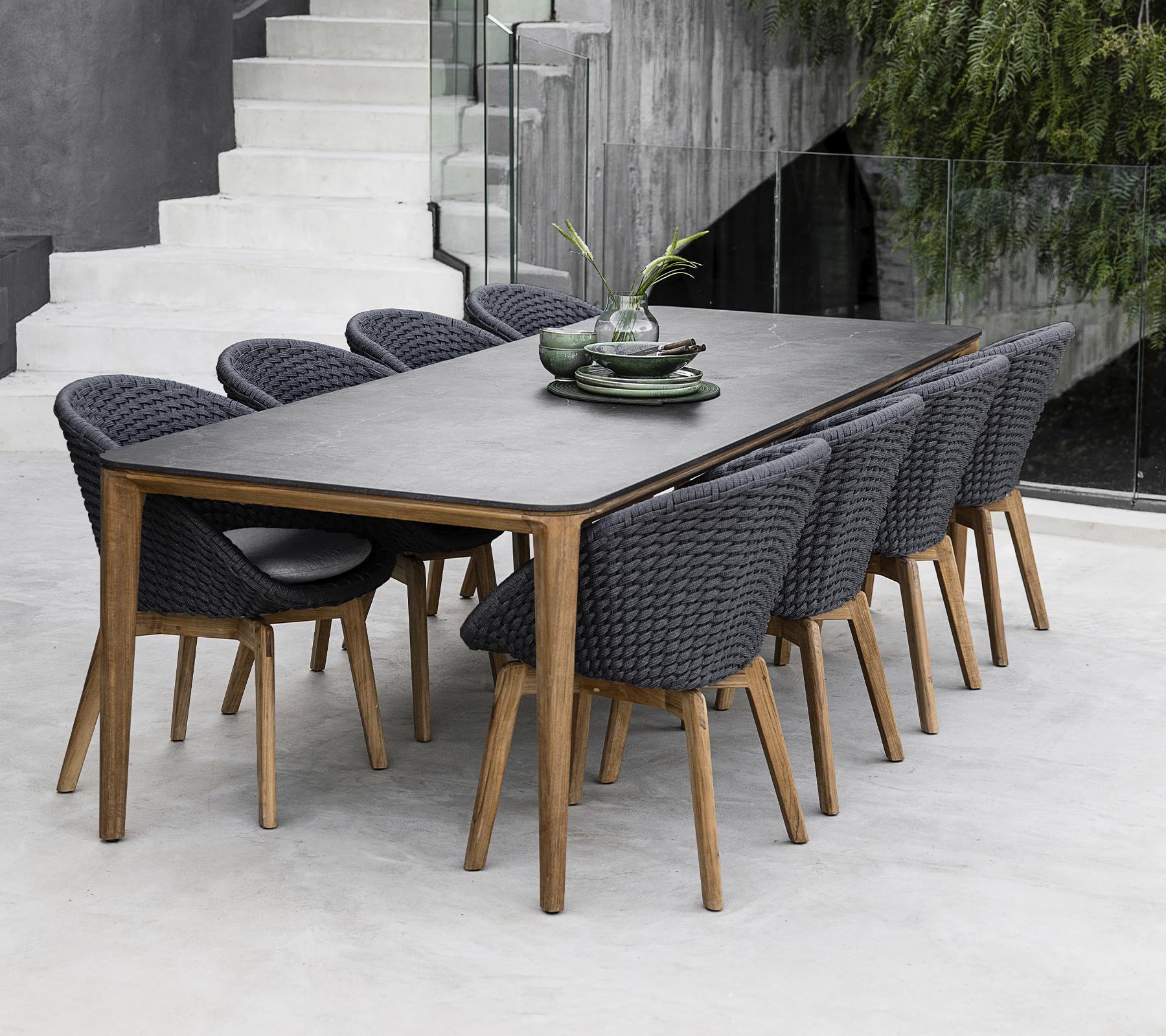 Une table moderne entourée de huit chaises élégantes, ornée de plantes décoratives sur la table dans un cadre épuré et minimaliste.