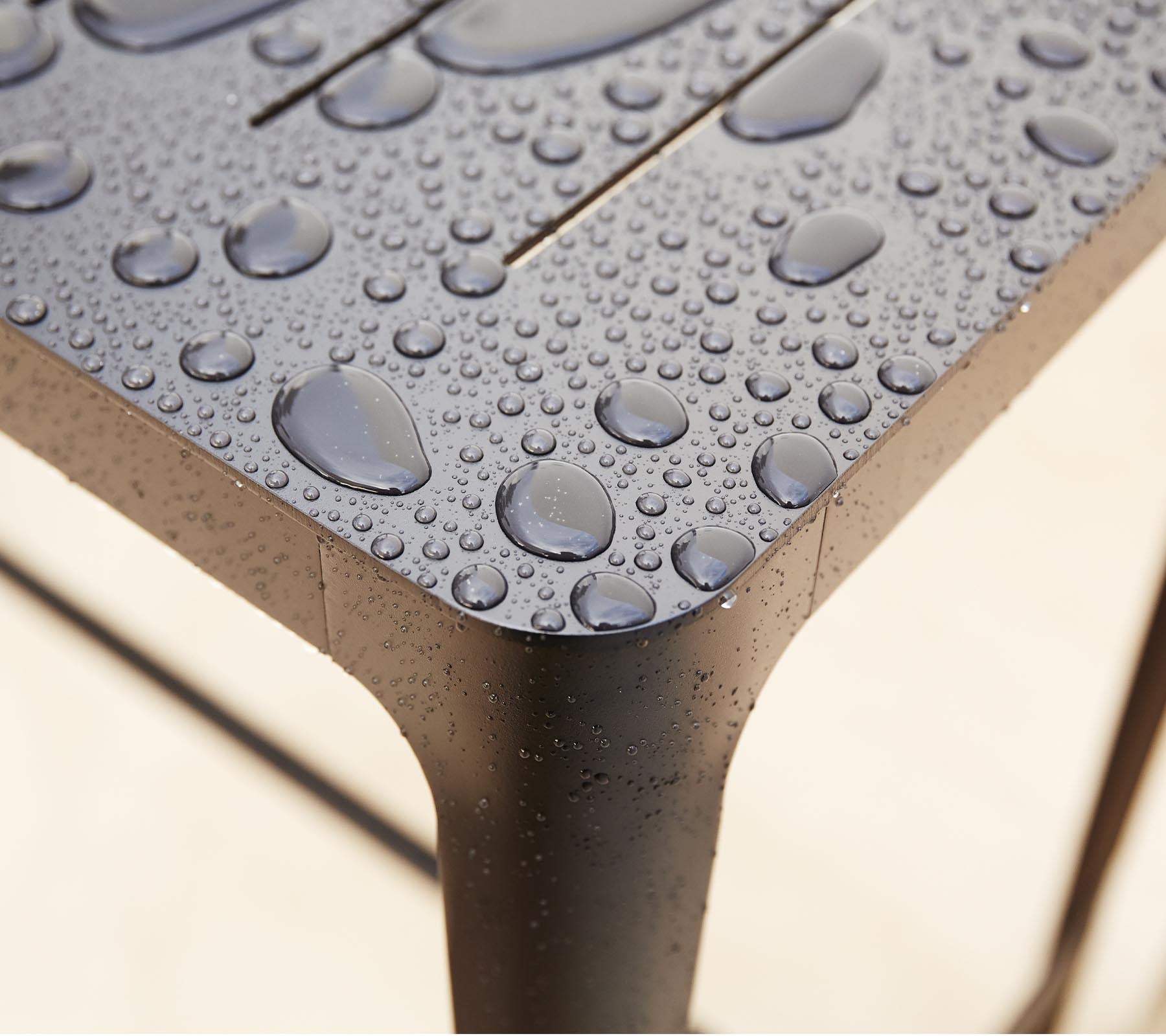 Gros plan d'une surface texturée avec des gouttes d'eau, mettant en valeur le design épuré et les détails du matériau.