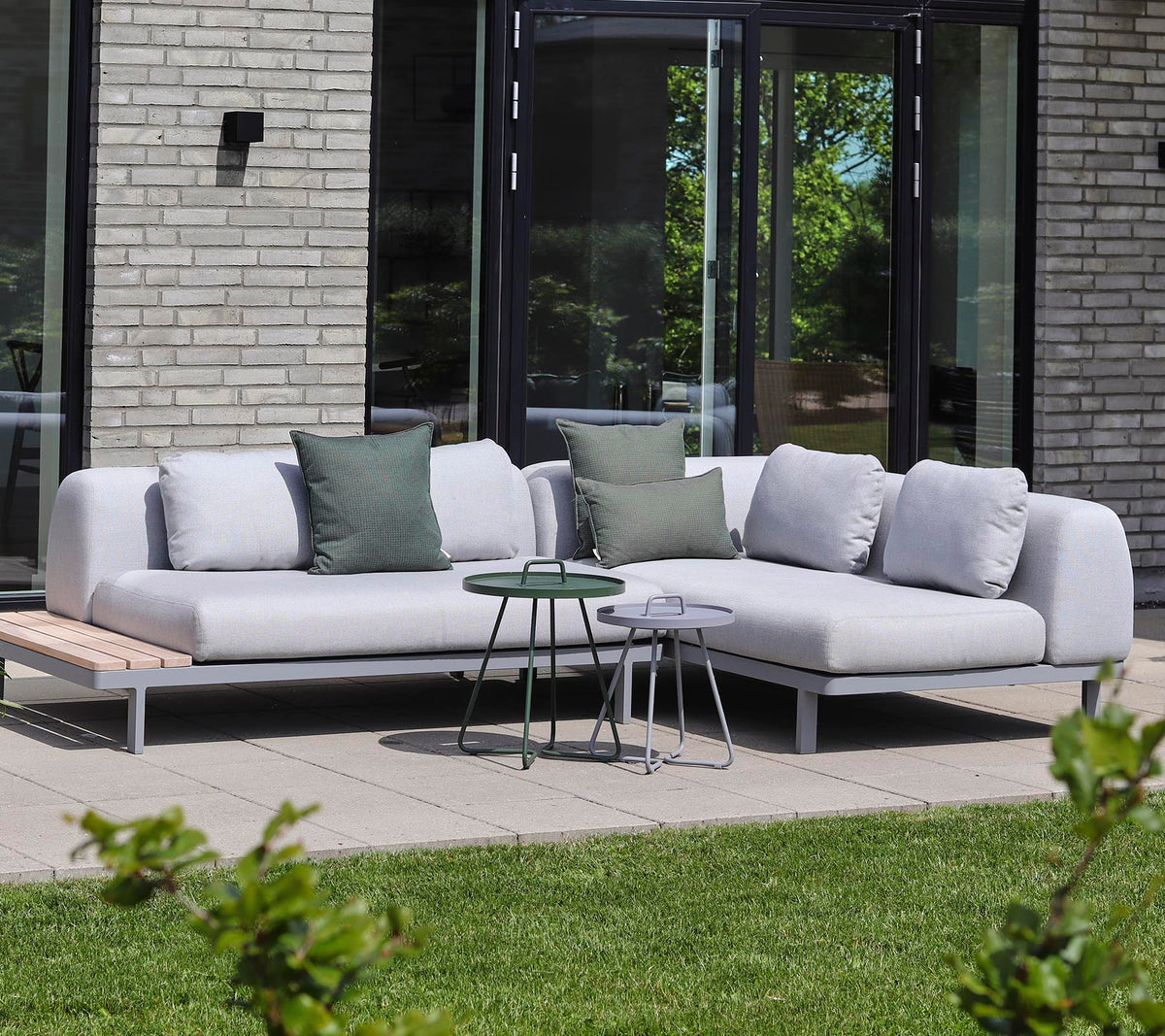Canapé moderne en tissu clair avec des coussins décoratifs, associé à de petites tables d'appoint dans un cadre tranquille.