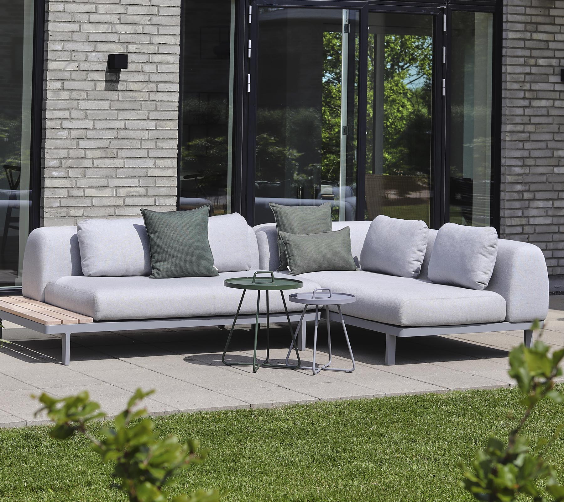 Canapé moderne en tissu clair avec des coussins décoratifs, associé à de petites tables d'appoint dans un cadre tranquille.
