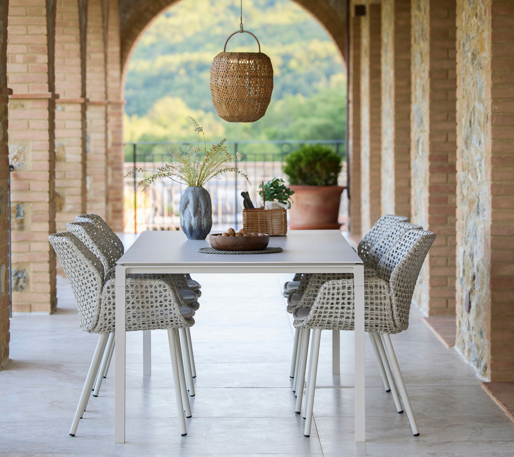 Un coin repas avec une table Pure entourée de chaises de salle à manger Vibe, agrémenté d'une lampe Illusion Glow suspendue et d'éléments décoratifs.