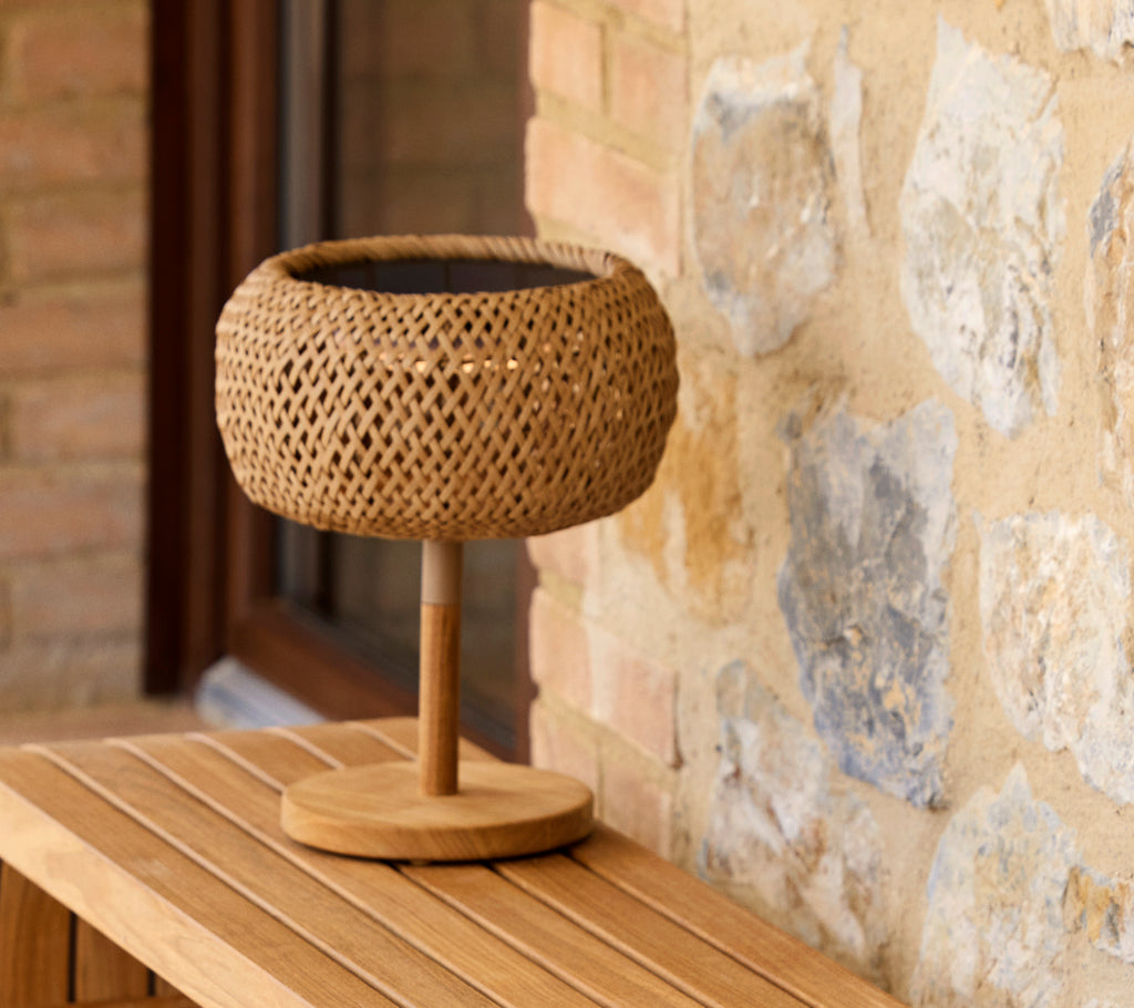 Lampe de table en forme de lanterne tissée avec une base en bois, ajoutant une lueur chaleureuse à un cadre rustique. Parfaite pour un éclairage douillet.
