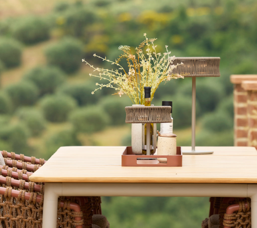 Une table à manger élégante avec une lampe illusion et un vase de fleurs, créant un centre de table élégant dans un cadre serein.