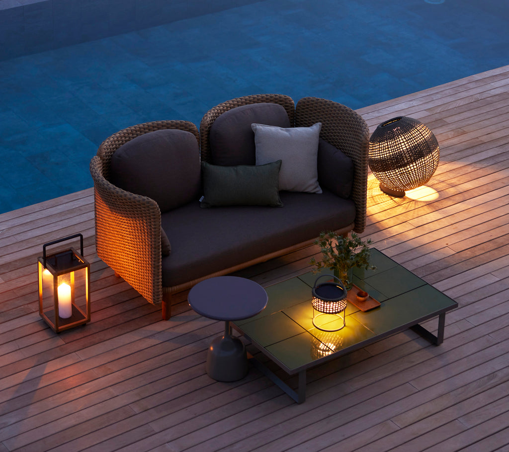Coin salon cozy avec une lampe d'illusion ronde, une table basse en verre et des éléments décoratifs, créant une ambiance chaleureuse.