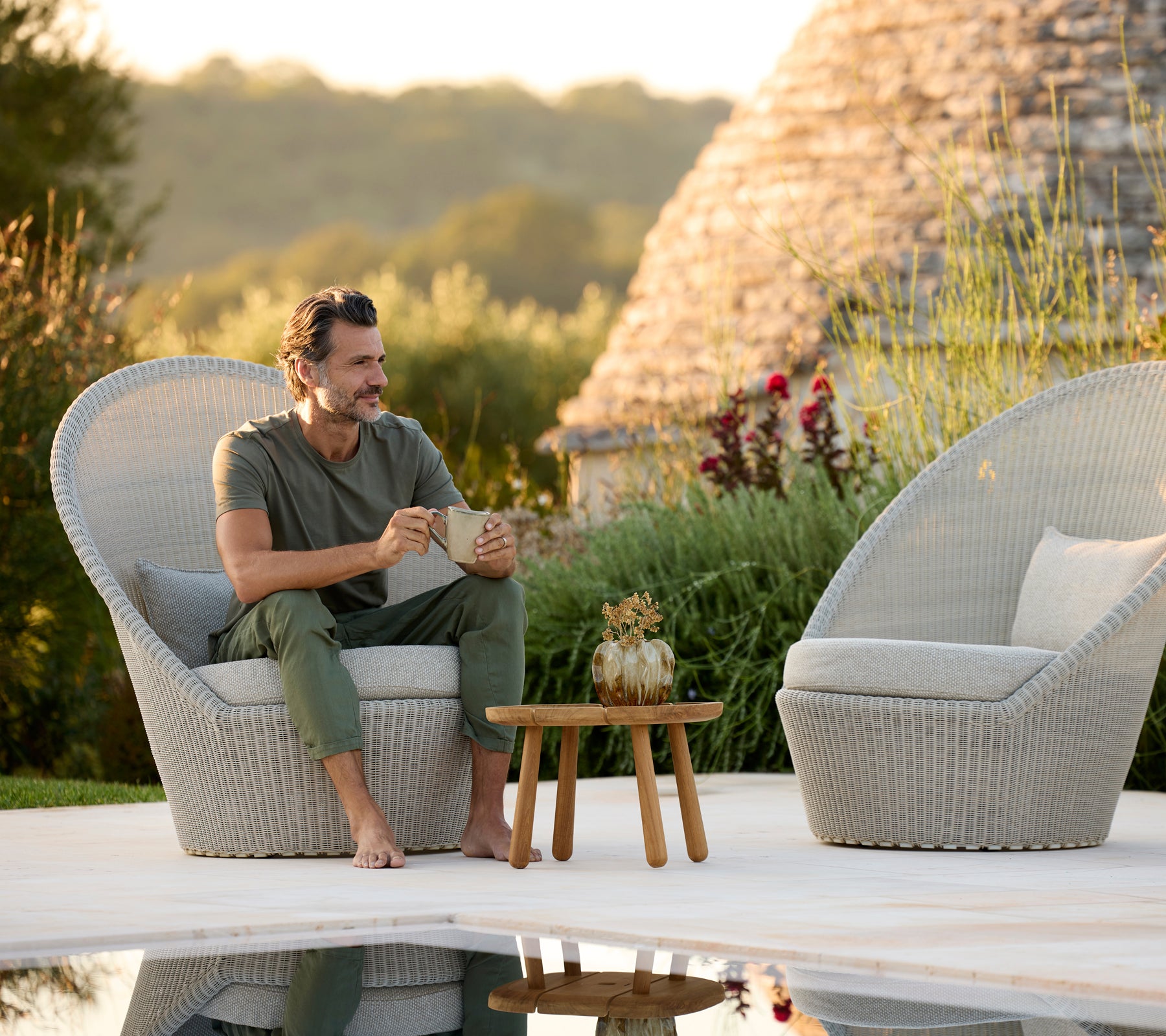 Chaises longues grises modernes avec une table en bois à côté d'une piscine.