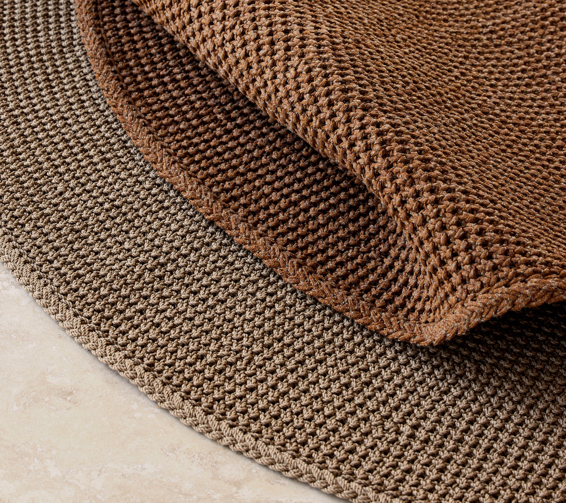 Tapis tricoté d'un diamètre de 200 cm, présentant un motif brun texturé et une apparence en couches.