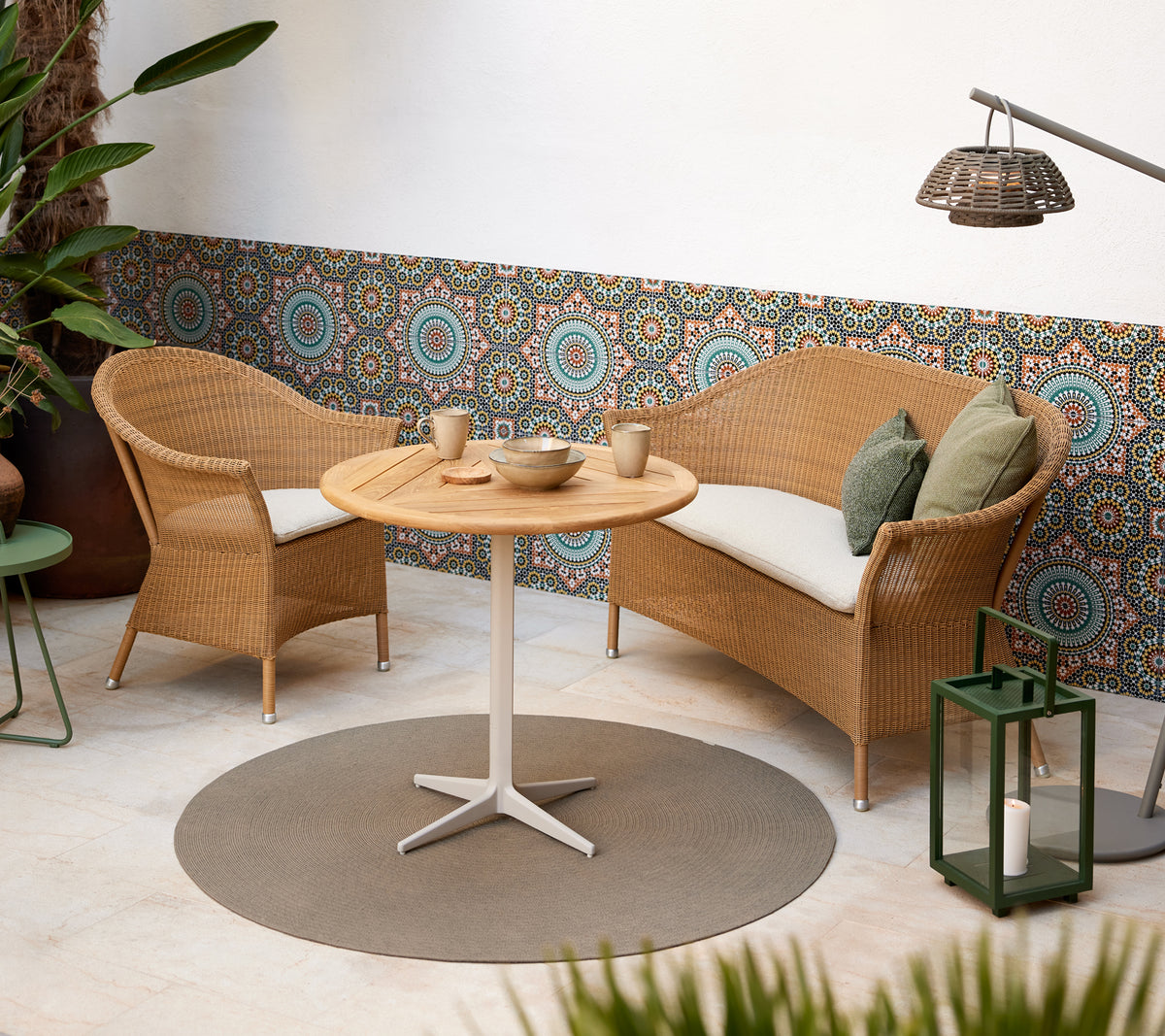 Un coin salon confortable avec des chaises en osier et une table ronde, complété par des motifs circulaires vifs en arrière-plan.