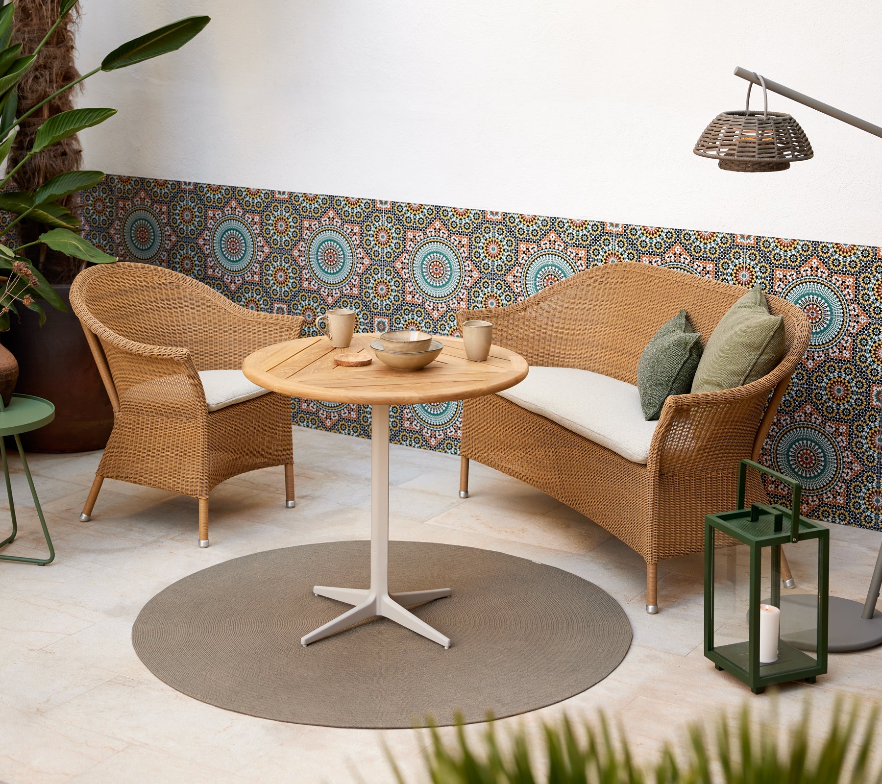 Un coin salon confortable avec des chaises en osier et une table ronde, complété par des motifs circulaires vifs en arrière-plan.