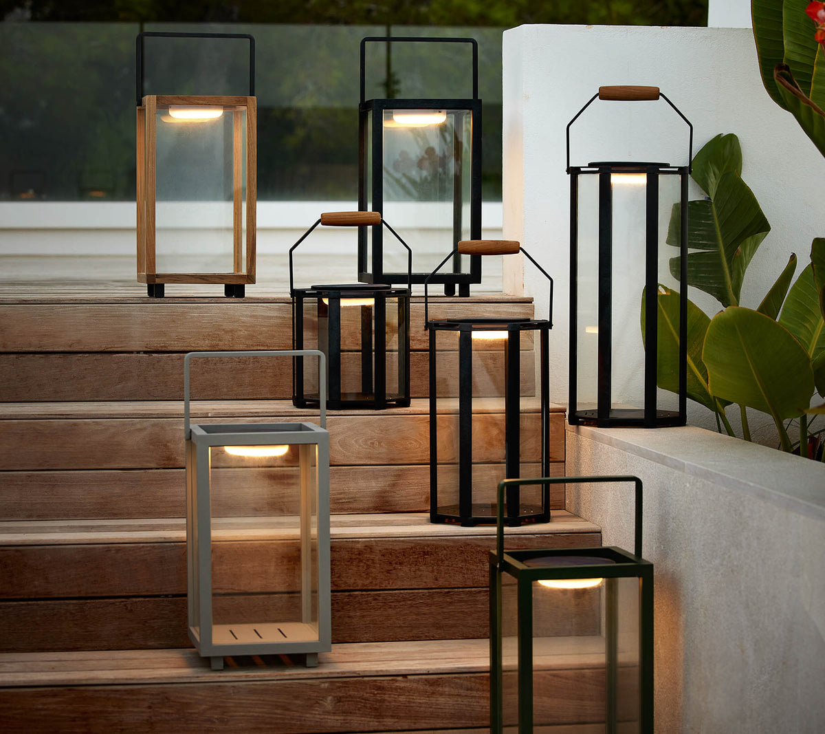 Une collection de lanternes modernes dans divers styles et couleurs disposées sur un escalier, mettant en avant leur design élégant et leur éclairage chaleureux.