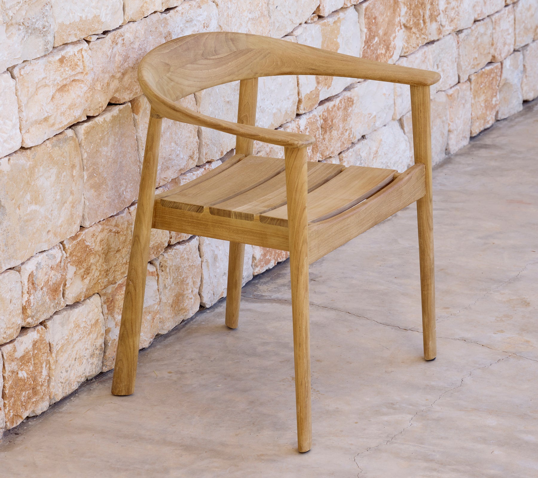 Chaise en bois moderne à côté d'un mur en pierre dans un cadre minimaliste.