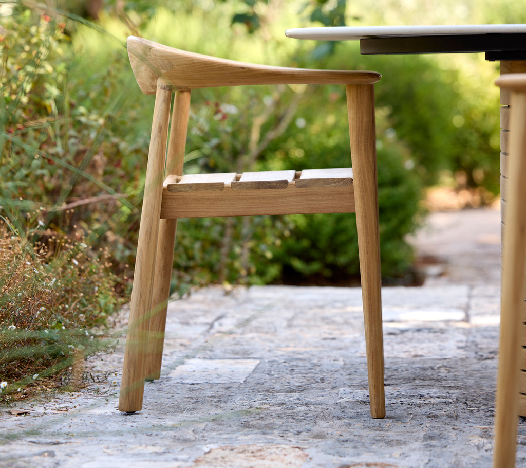 Chaise en bois moderne à côté d'une table noire dans un cadre extérieur.