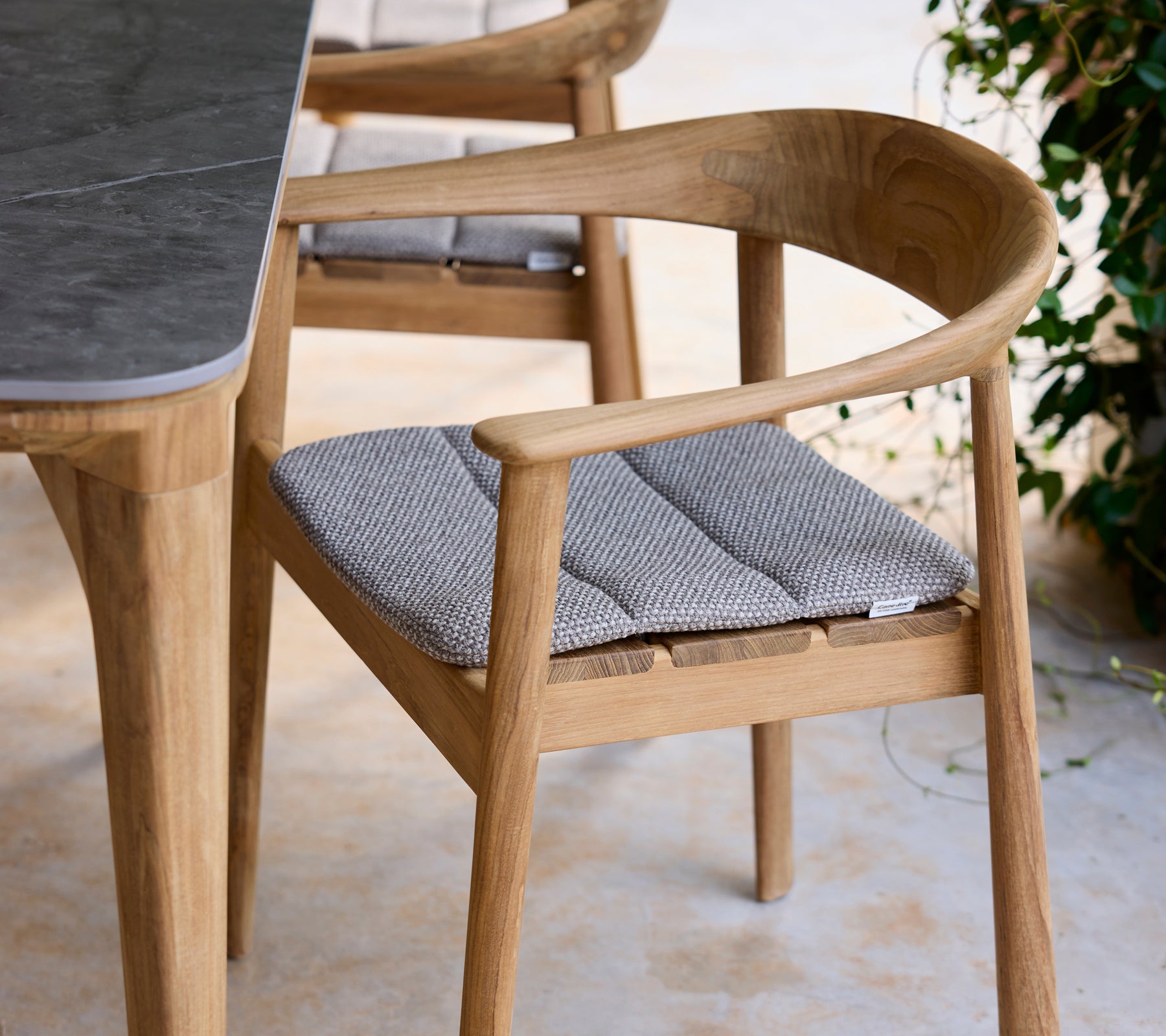Chaise en bois moderne avec coussin gris à côté d'une table dans un cadre de salon.