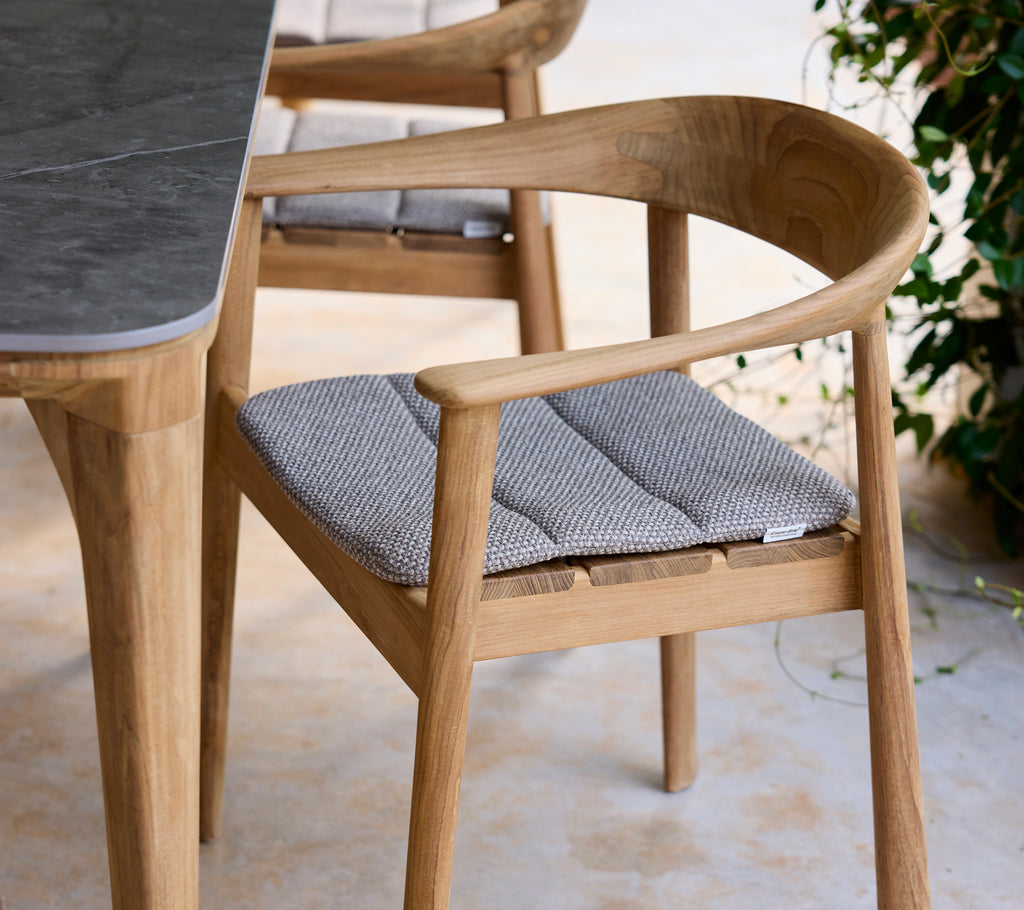 Chaise en bois moderne avec coussin gris à côté d'une table dans un cadre de salon.