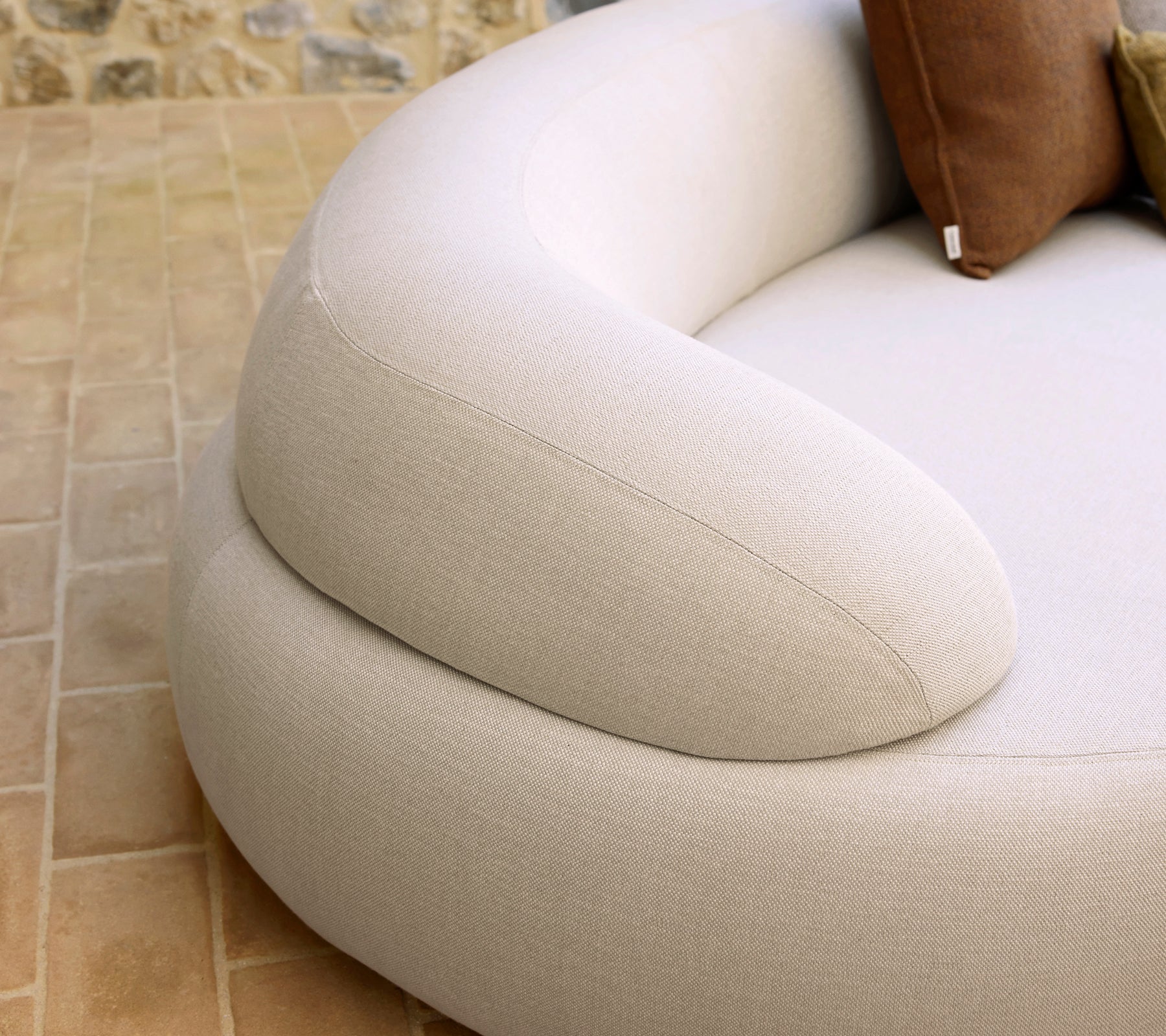 Accoudoirs doux et arrondis d'un meuble confortable, avec un tissu léger et des coussins décoratifs assortis.