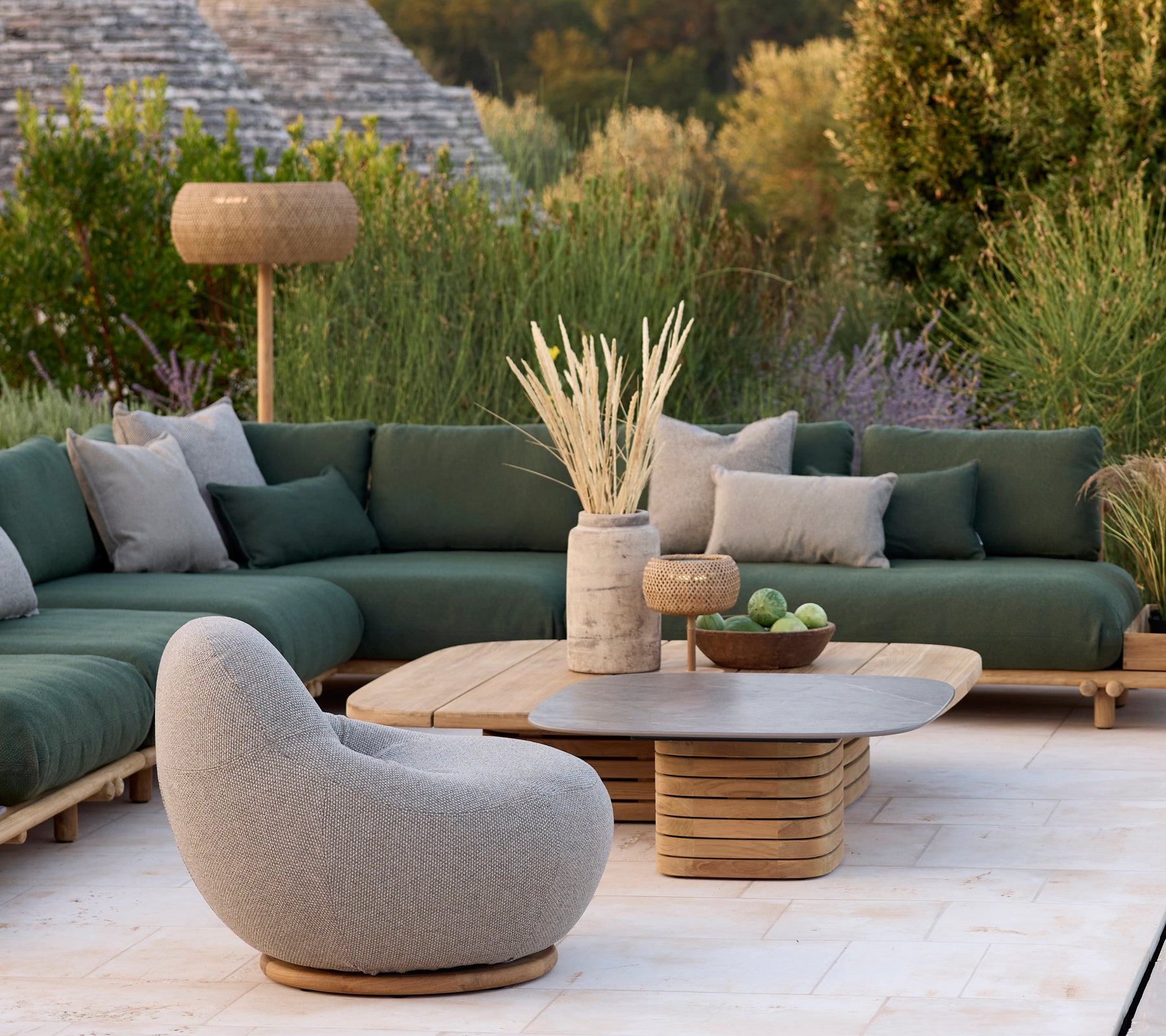 Espace lounge moderne avec un canapé vert, une chaise grise et une table basse ronde.