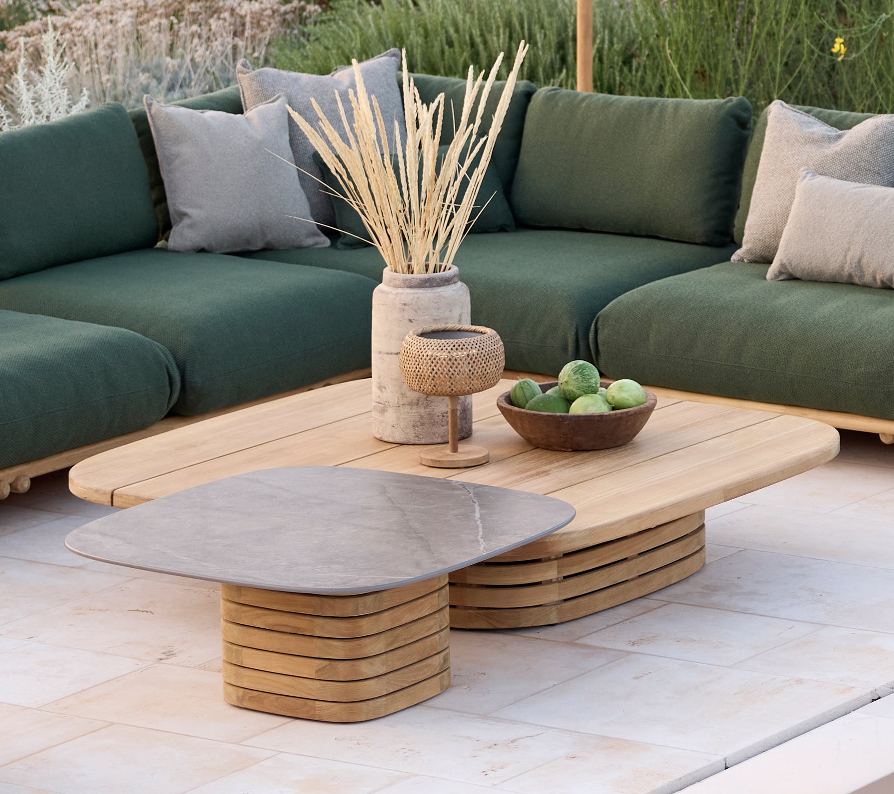 Espace lounge moderne avec un canapé vert avec des coussins, une table basse en bois et des objets décoratifs.