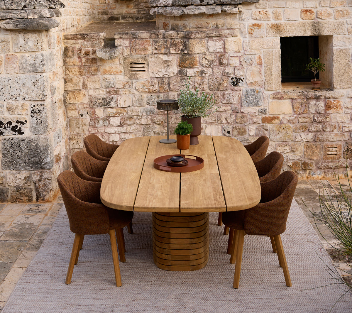 Table à manger en bois moderne entourée de chaises brunes dans un cadre rustique.