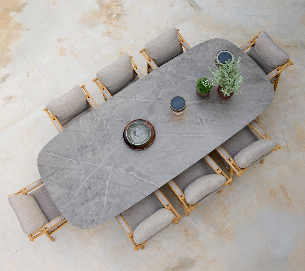 Aménagement de salle à manger moderne avec une table grise, des coussins beiges et des chaises en bois.
