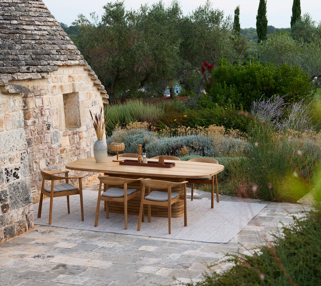 Table à manger en bois moderne entourée de chaises en bois dans un cadre de jardin extérieur.