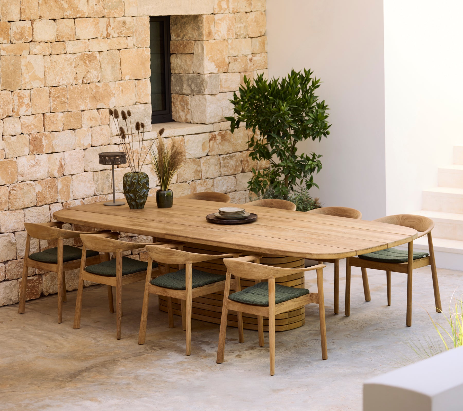 Table à manger en bois moderne avec des coussins verts et des chaises en bois dans un cadre minimaliste.