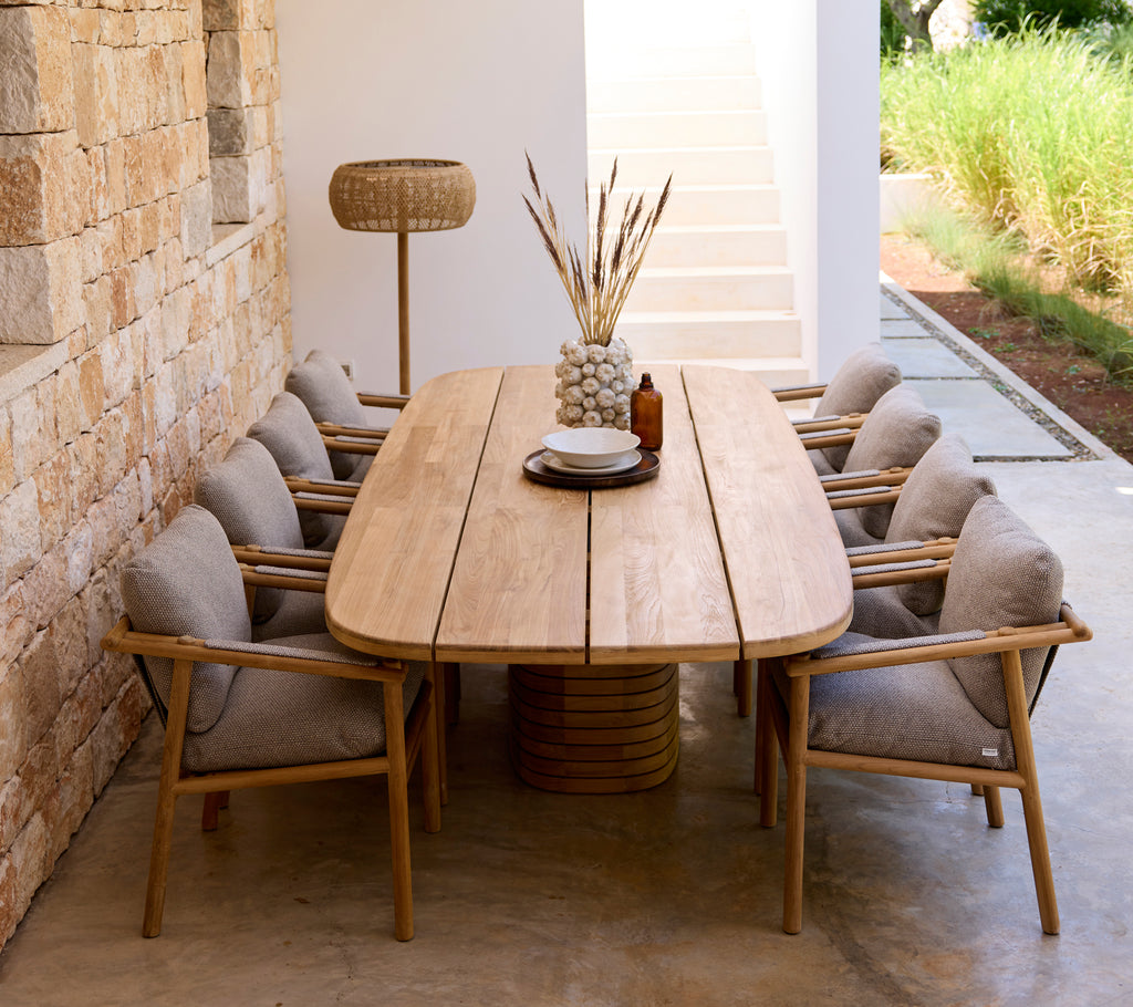 Agencement moderne de salle à manger avec table en bois, coussins gris et chaises en bois.