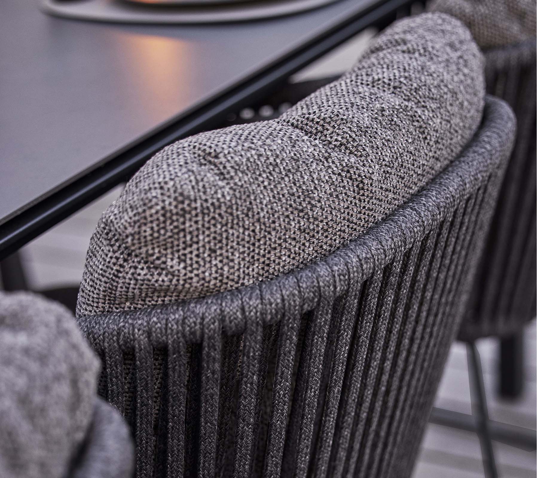 Gros plan d'un dossier de chaise texturé avec un coussin doux et rembourré, présentant un design à côtes verticales élégant.