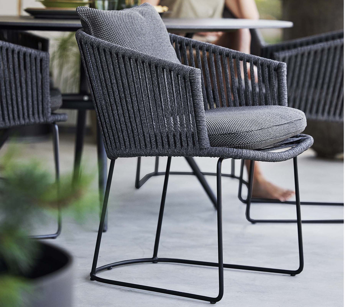 Chaise élégante avec un design tissé et un coussin doux, soutenue par un cadre métallique épuré, parfaite pour des espaces contemporains.