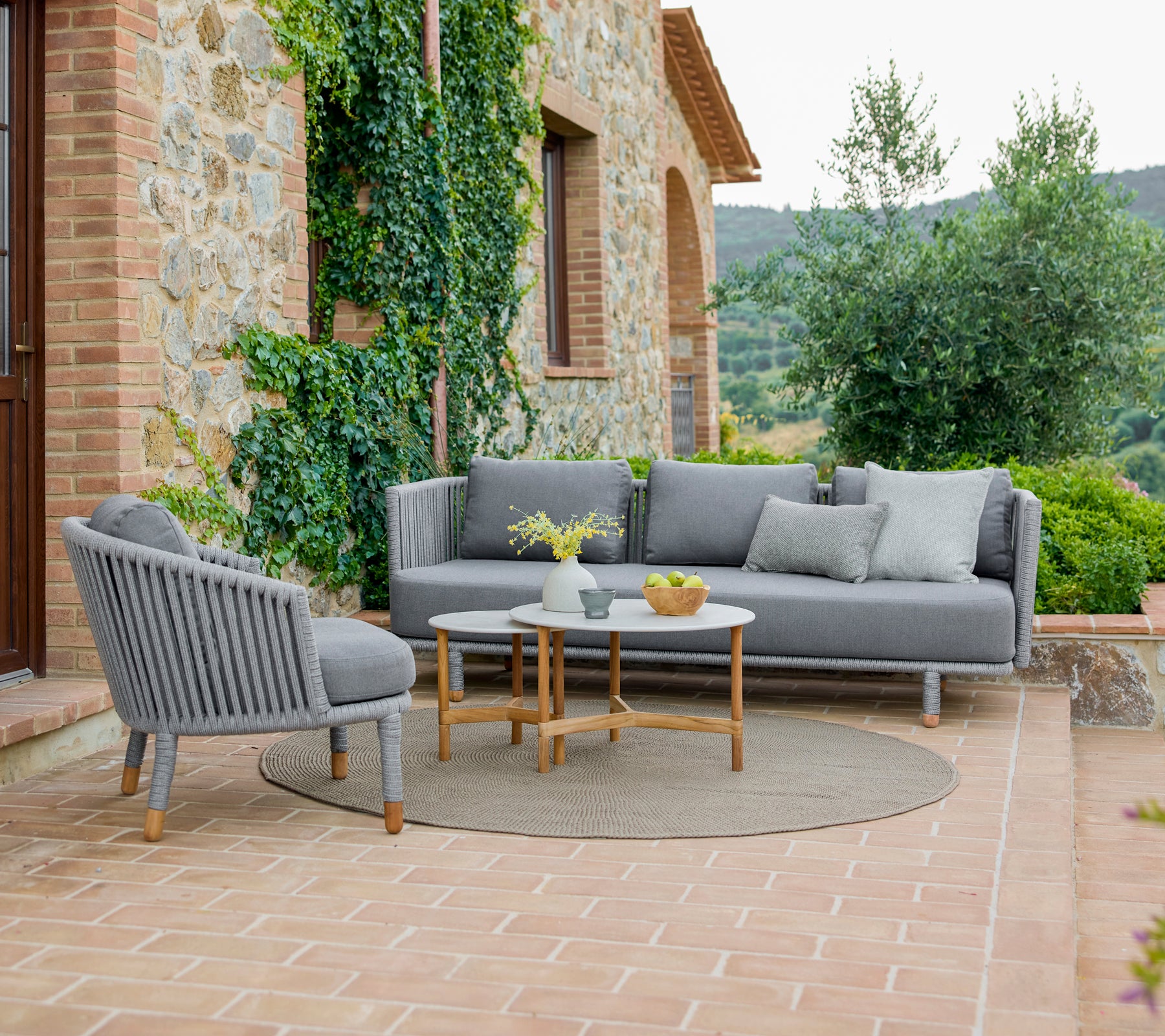 Fauteuil et canapé élégants avec une disposition conviviale, accompagnés de tables basses sleek, entourés de verdure.