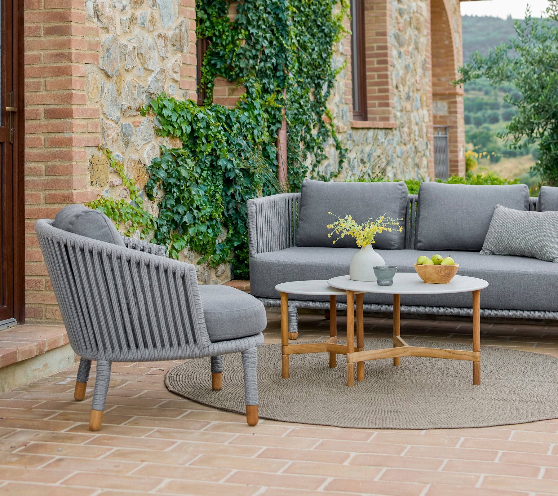 Un ensemble de fauteuils et de tables basses au design moderne, entouré de verdure et d'une atmosphère chaleureuse et accueillante.